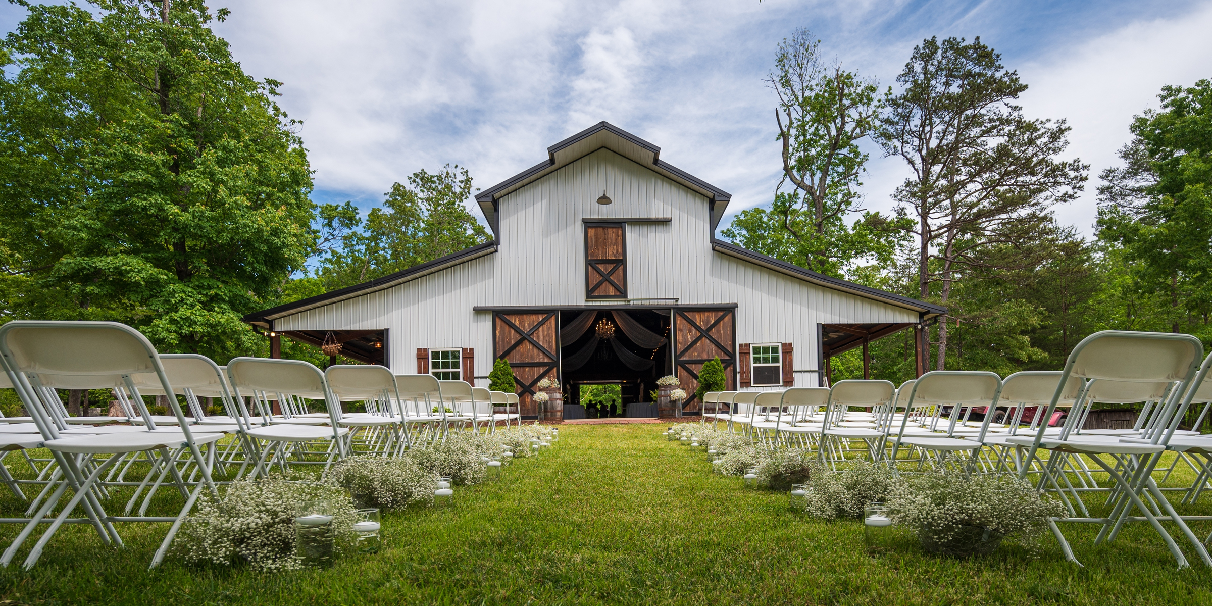 A rustic barn wedding setup with white chairs, baby's breath flowers, and a charming countryside backdrop | Source: Shutterstock