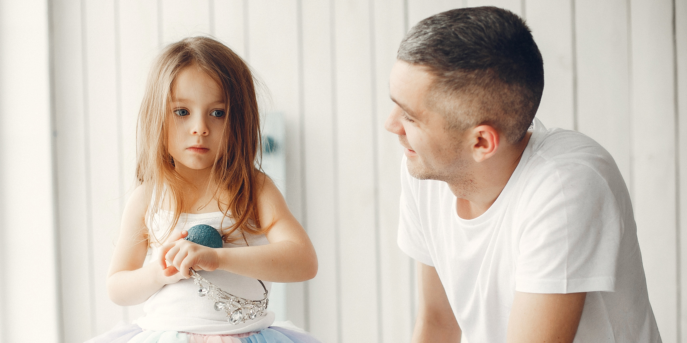 A father gently smiling at his daughter while she stares ahead, lost in thought | Source: Shutterstock
