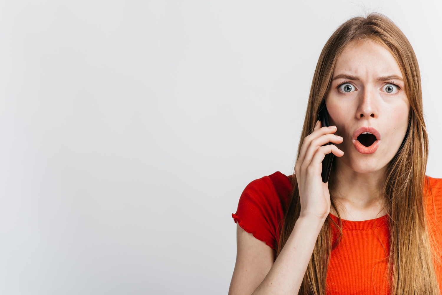 A startled woman talking on the phone | Source: Freepik