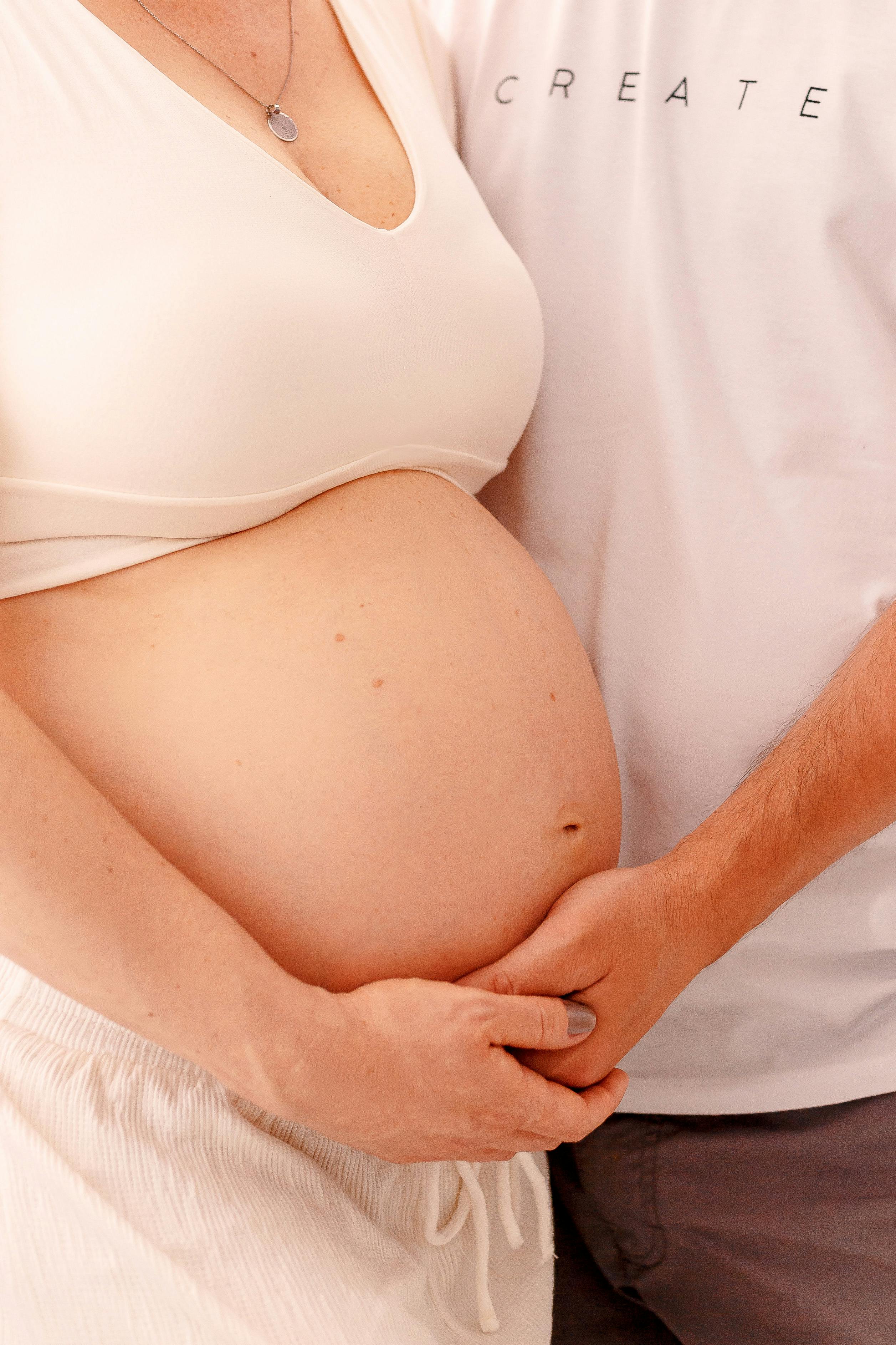 A woman placing a man's hand on her pregnant belly | Source: Pexels