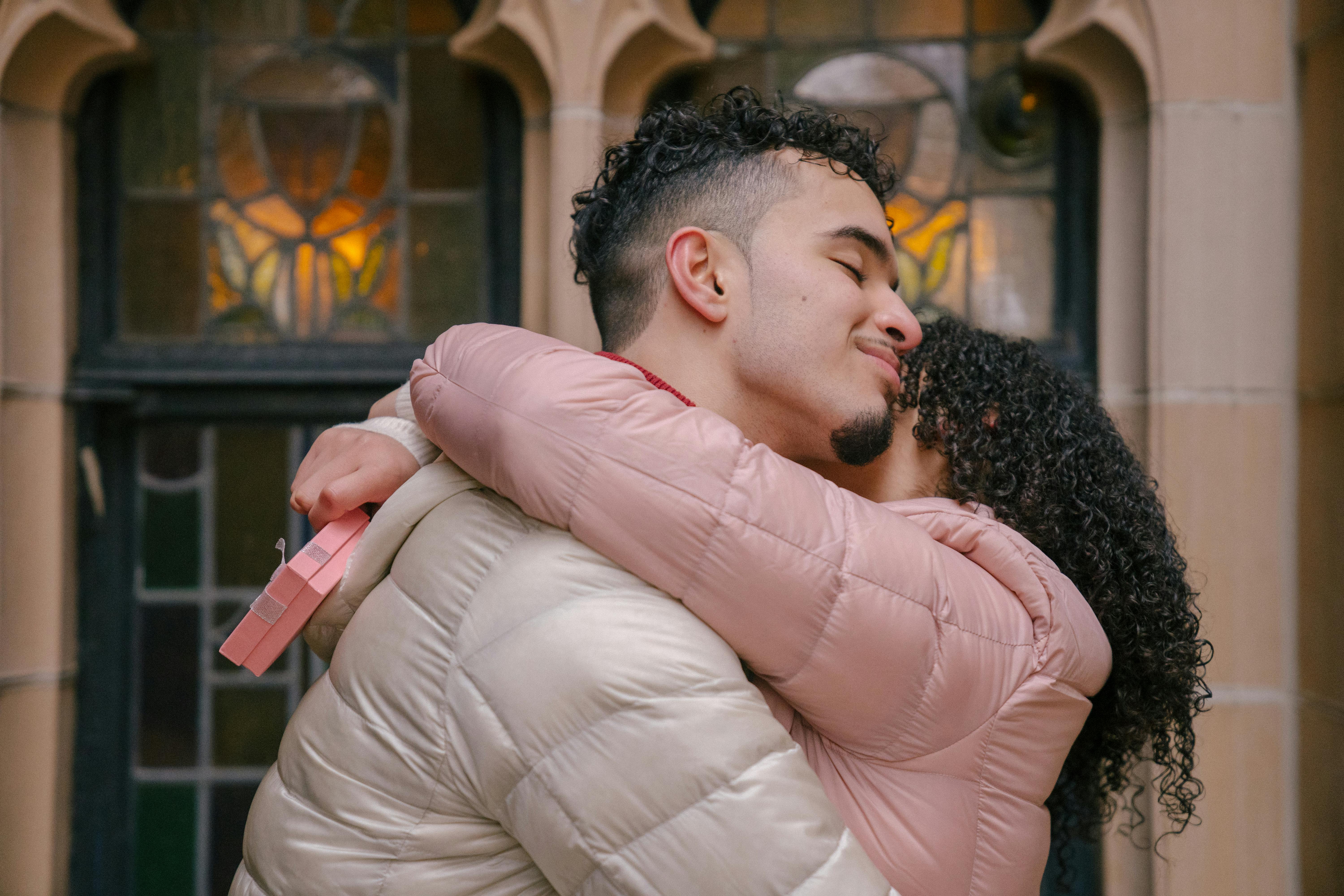 A couple embracing while a woman holds a gift | Source: Pexels