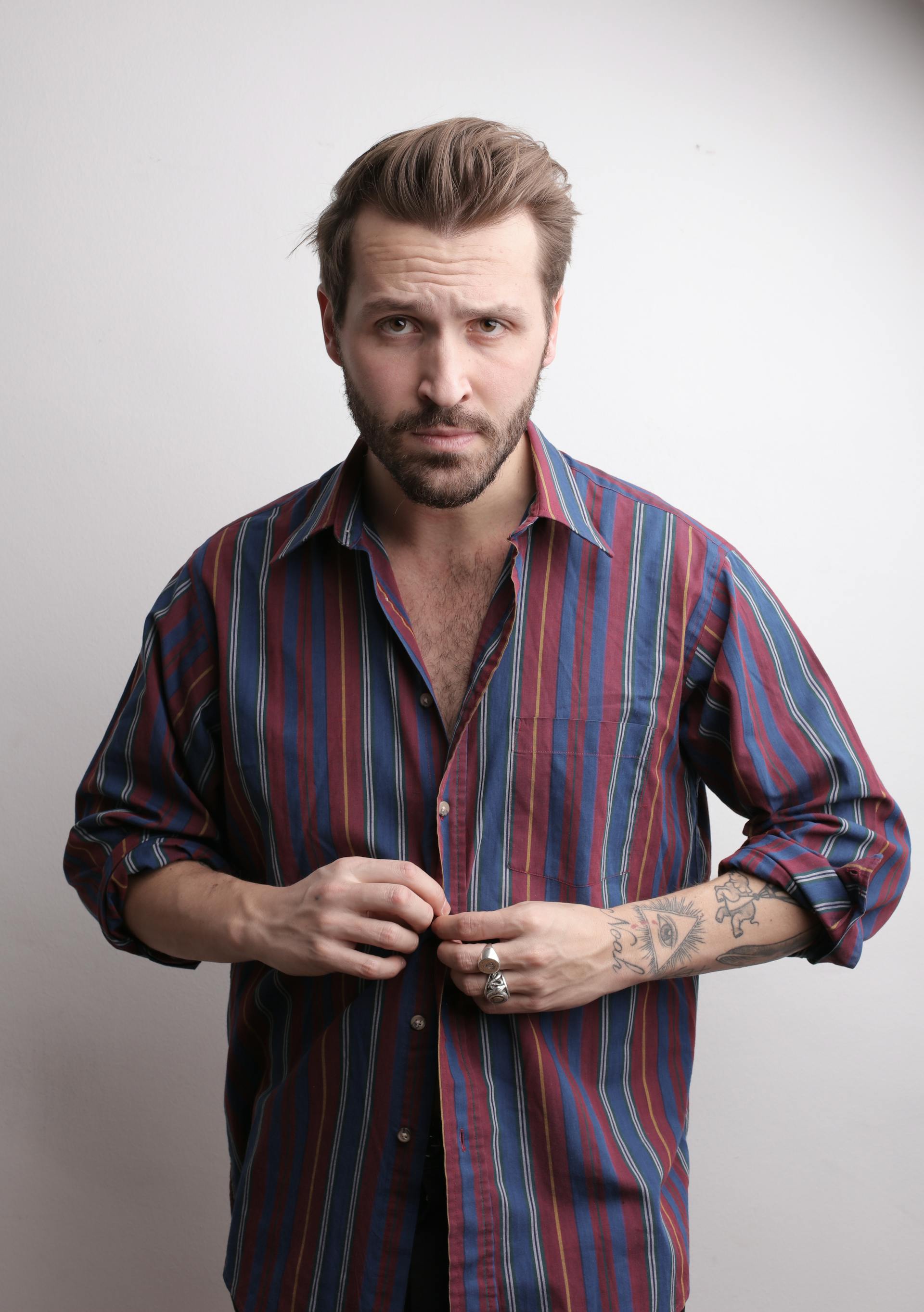 A frowning man buttoning his shirt up | Source: Pexels
