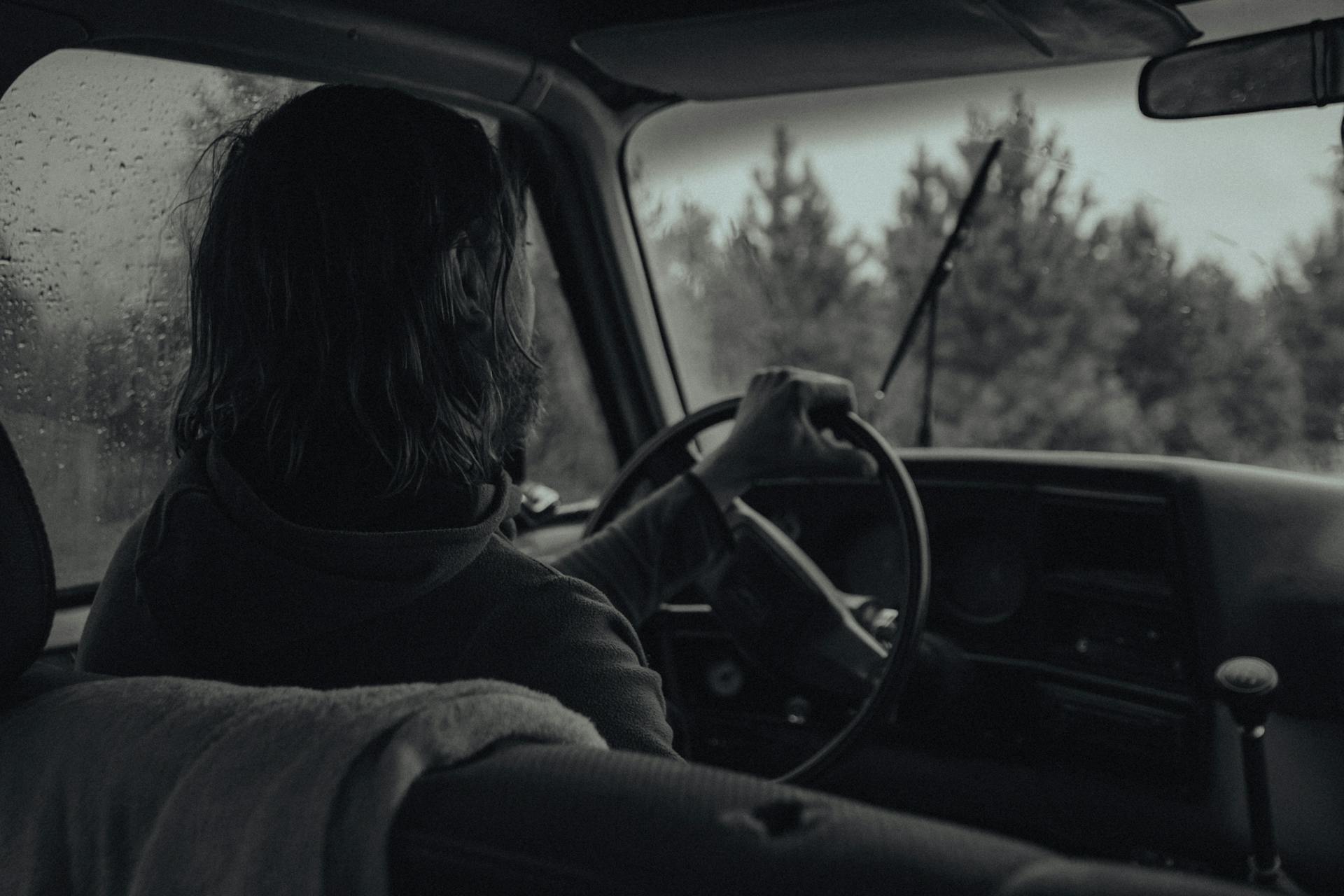 A grayscale photo of a woman driving a car in rain | Source: Pexels