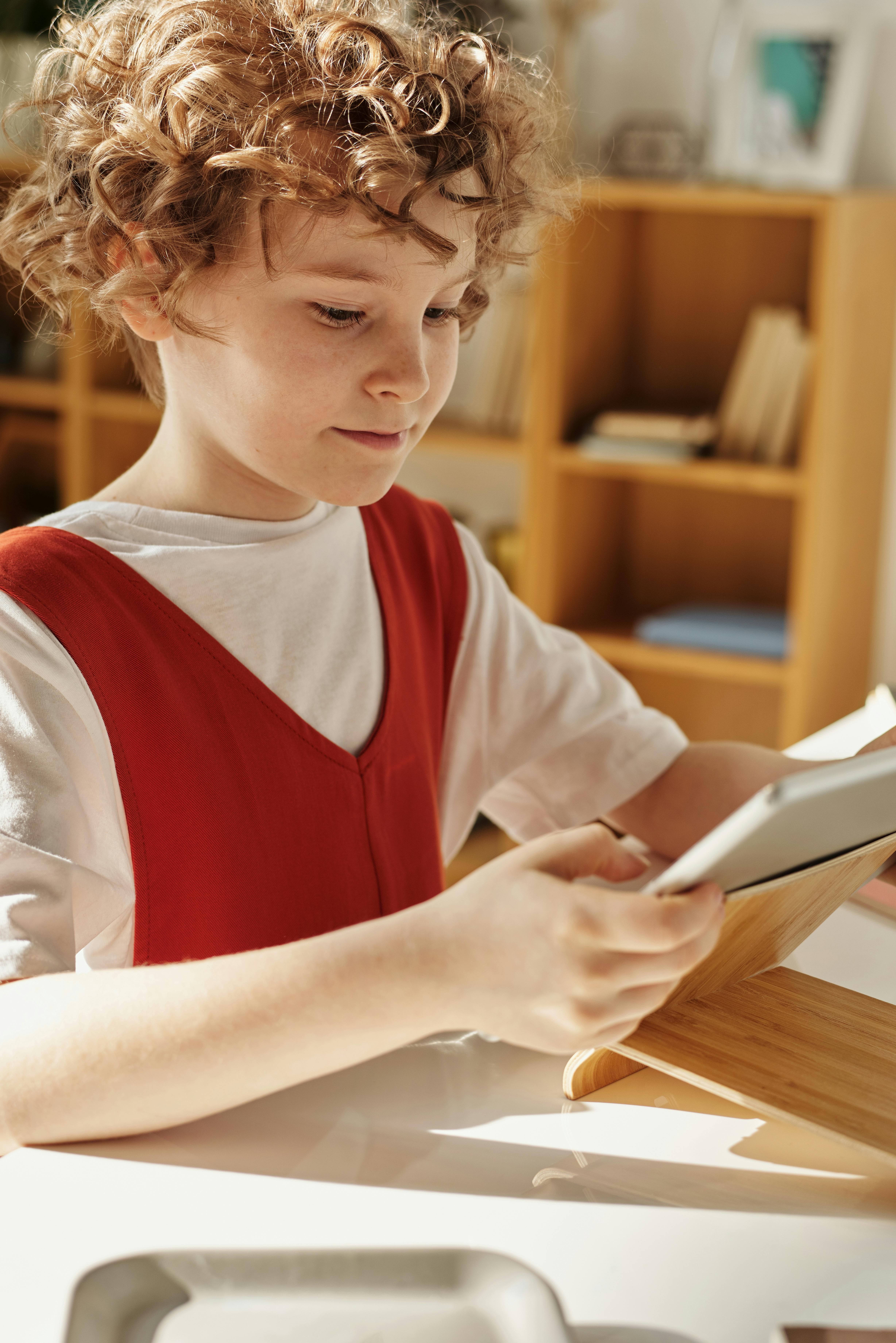 A child using a tablet on a wooden stand | Source: Pexels