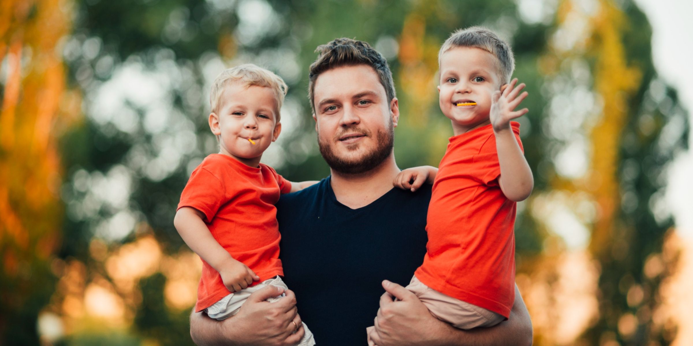 A man holding his twin sons | Source: Freepik
