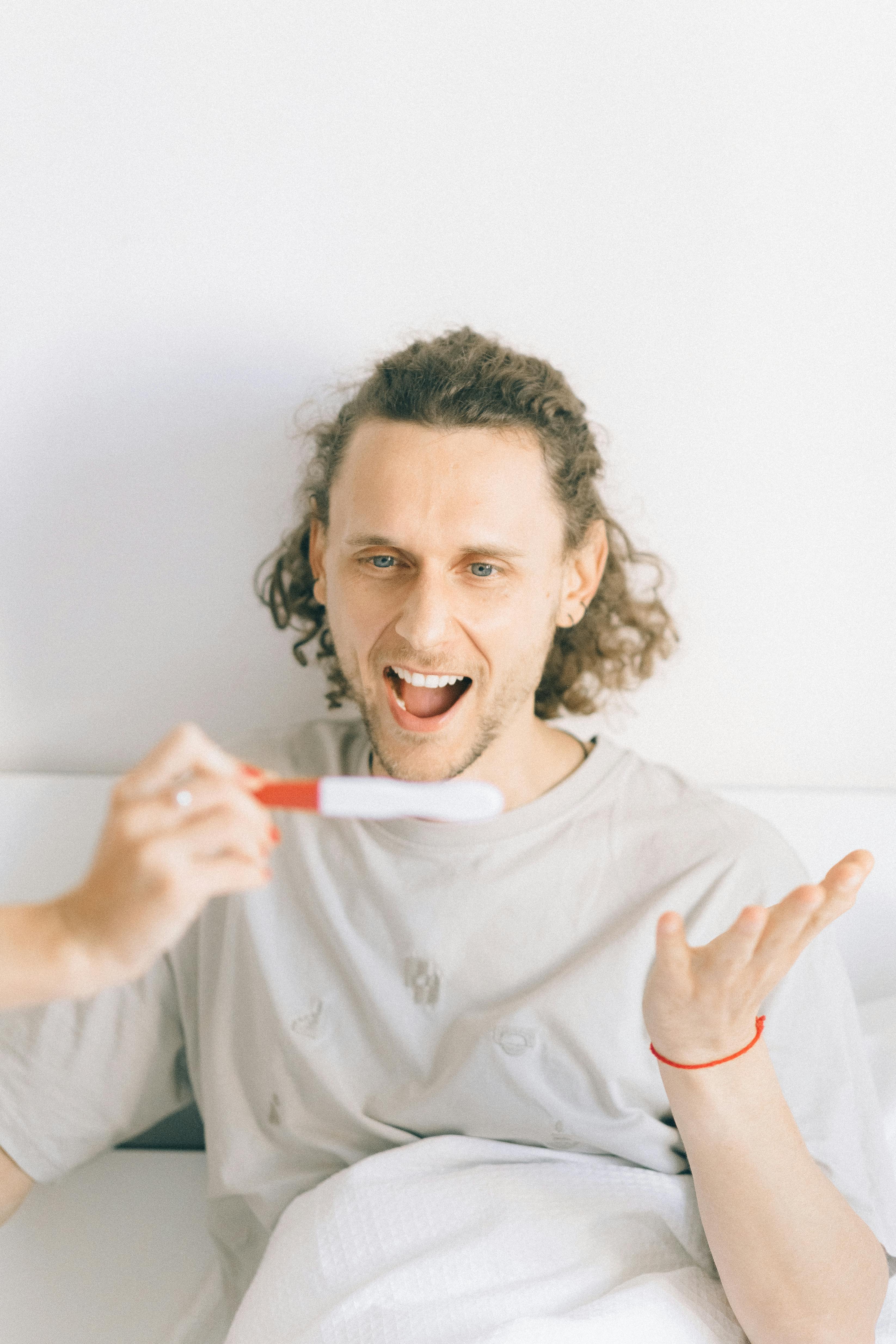 An excited man looking at a pregnancy test | Source: Pexels