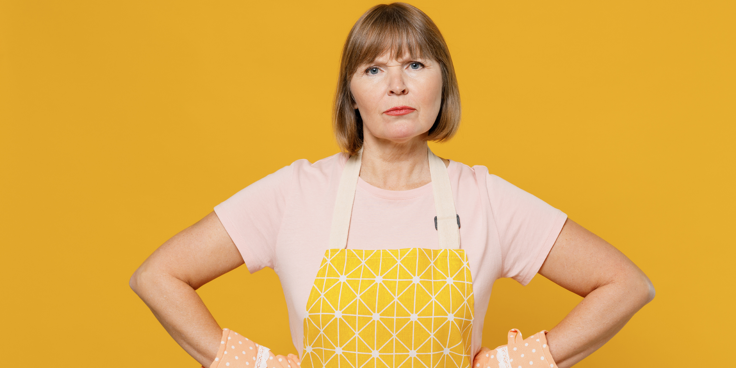 An upset woman wearing an apron and oven mitts | Source: Shutterstock