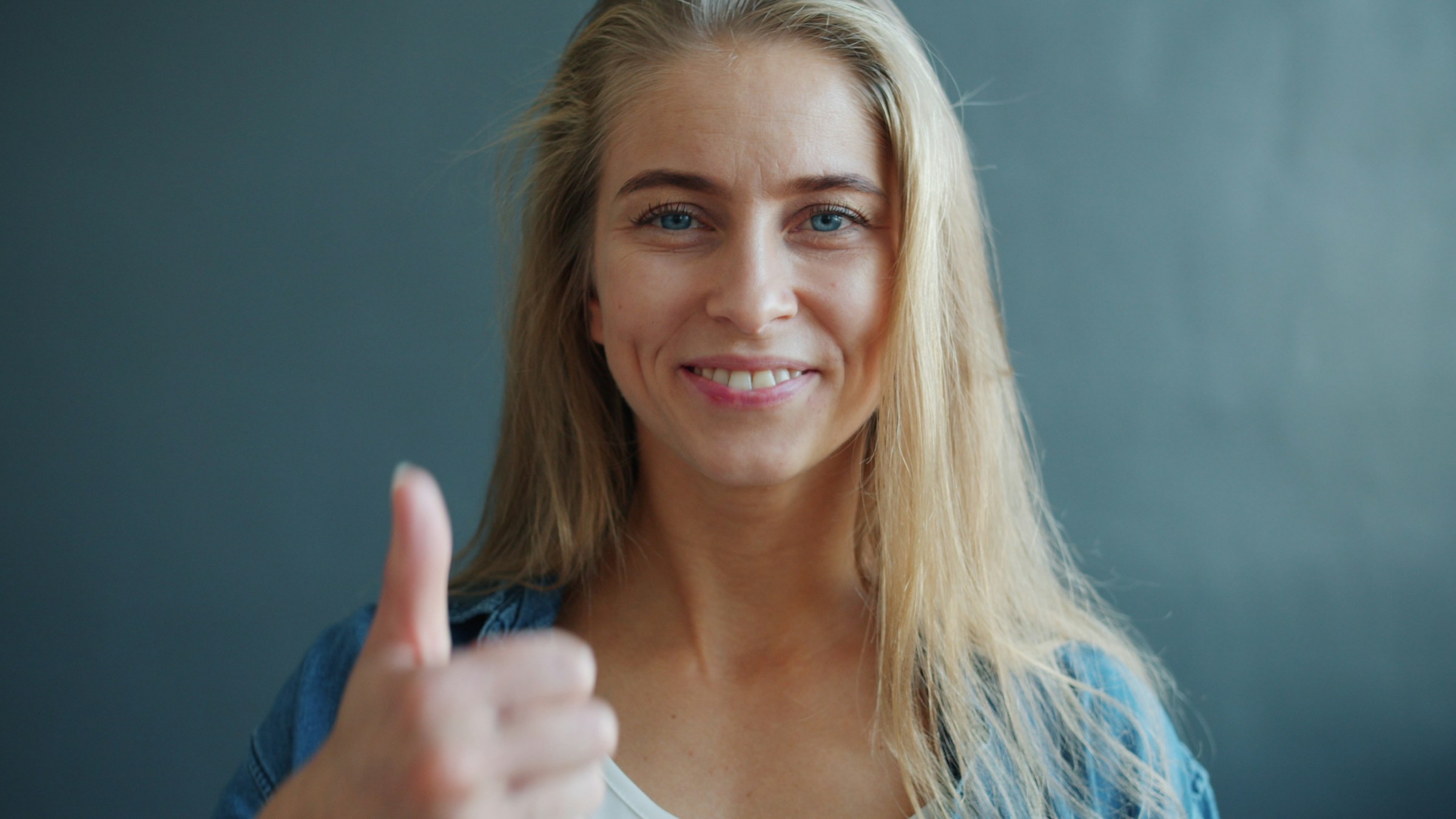 A smiling woman showing a thumbs-up sign | Source: Unsplash