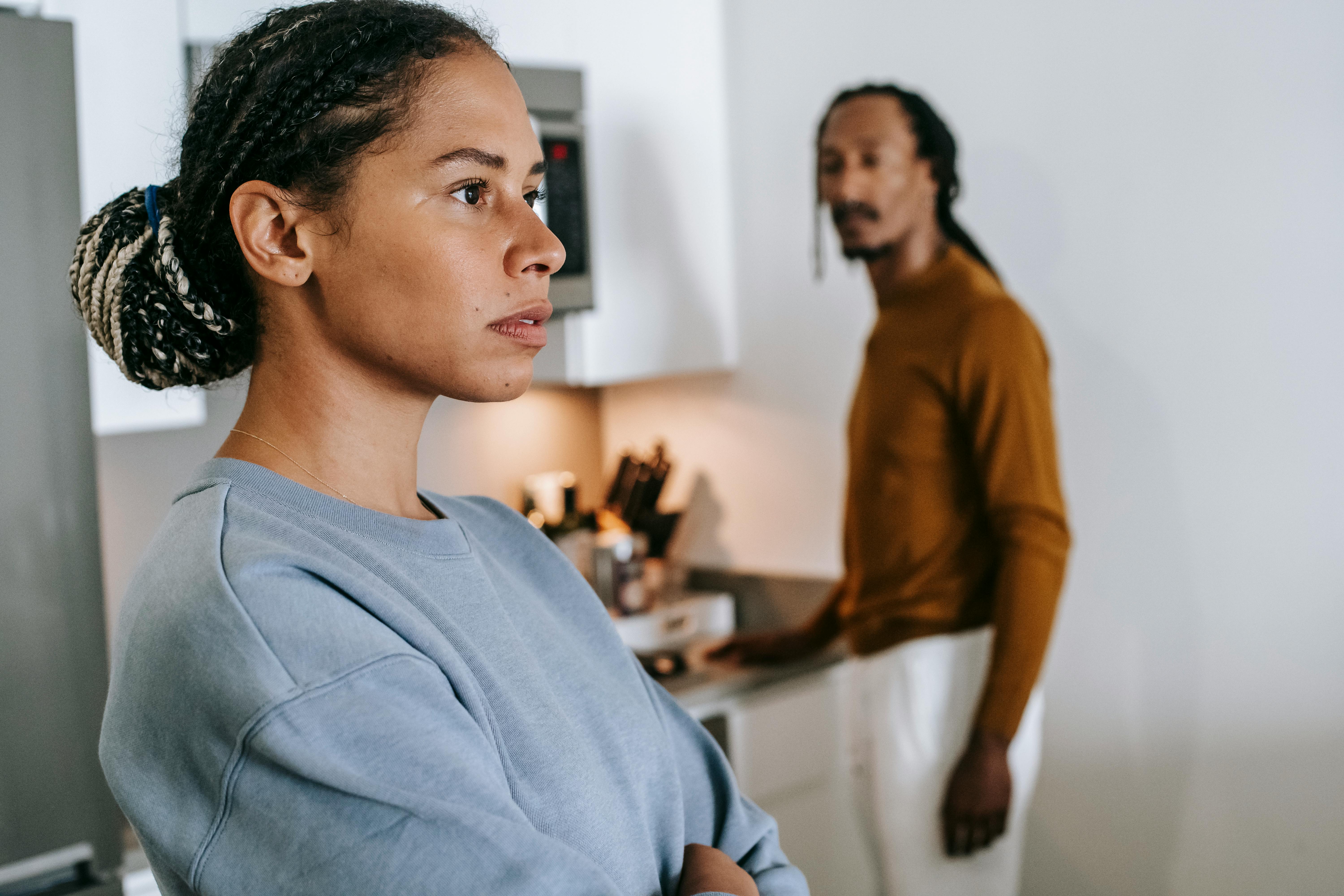 An upset woman with a man in the background | Source: Pexels