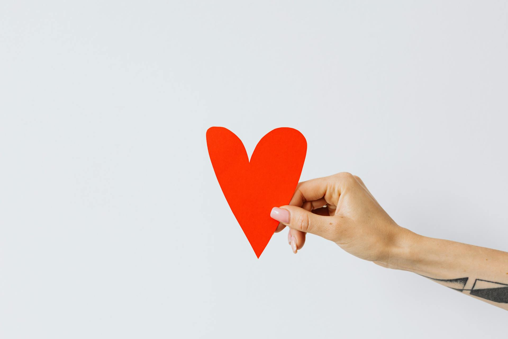 A woman holding a red paper heart | Source: Pexels