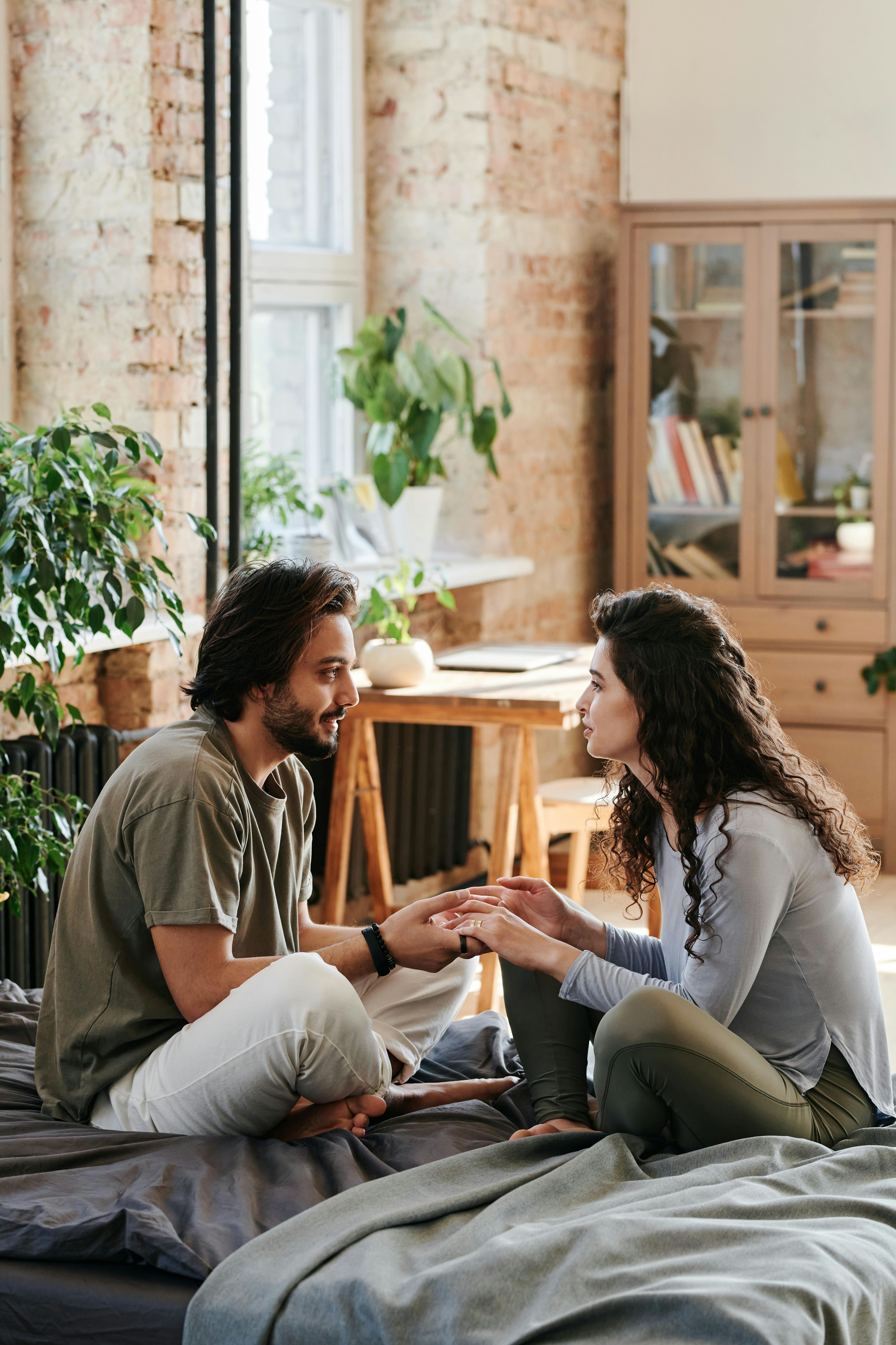 Couple sitting on the bed while having a conversation | Source: Pexels