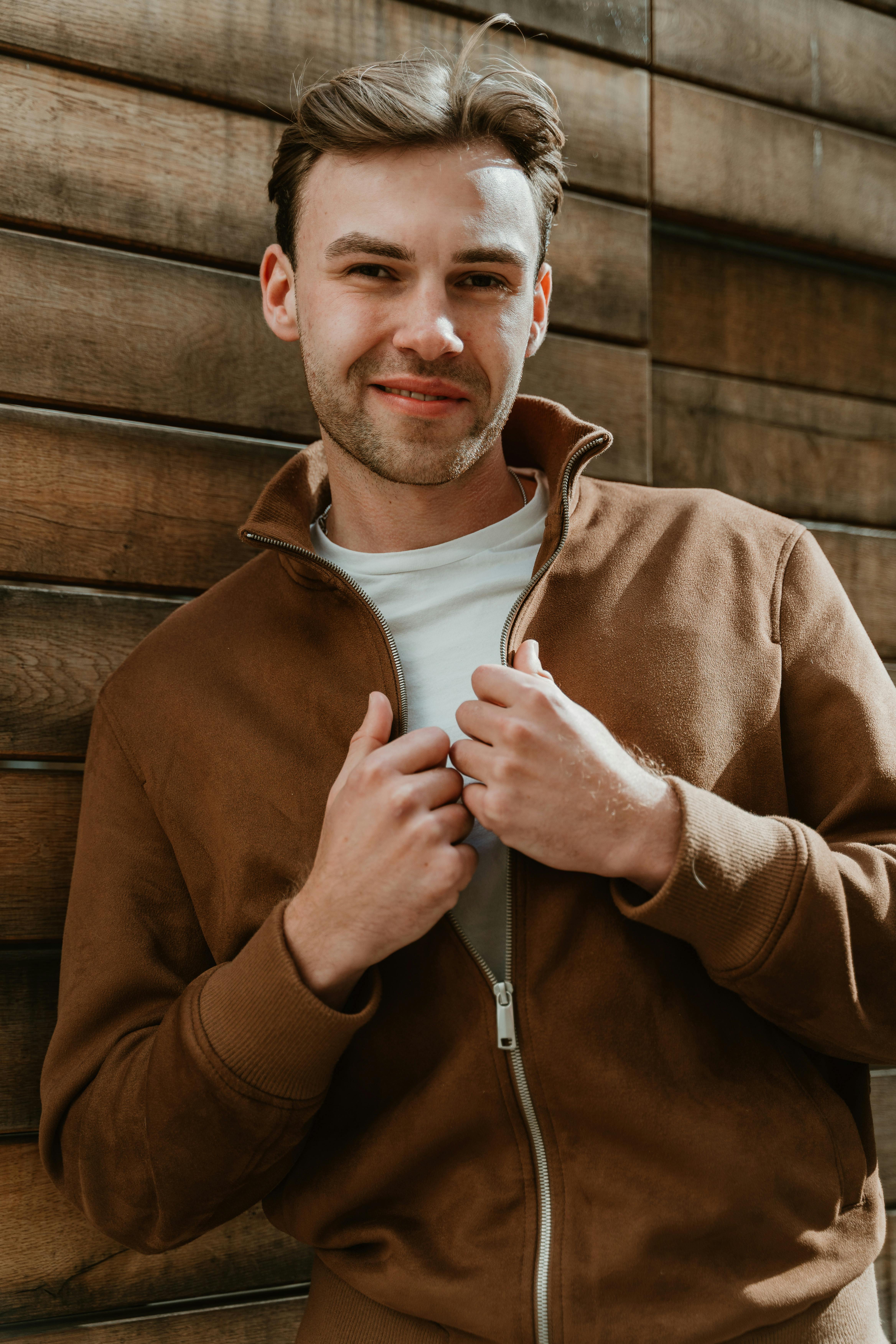 A smiling young man wearing a brown jacket | Source: Pexels