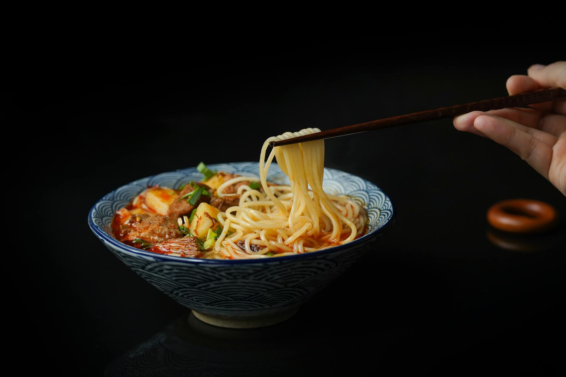 A person holding noodles with chopsticks | Source: Pexels