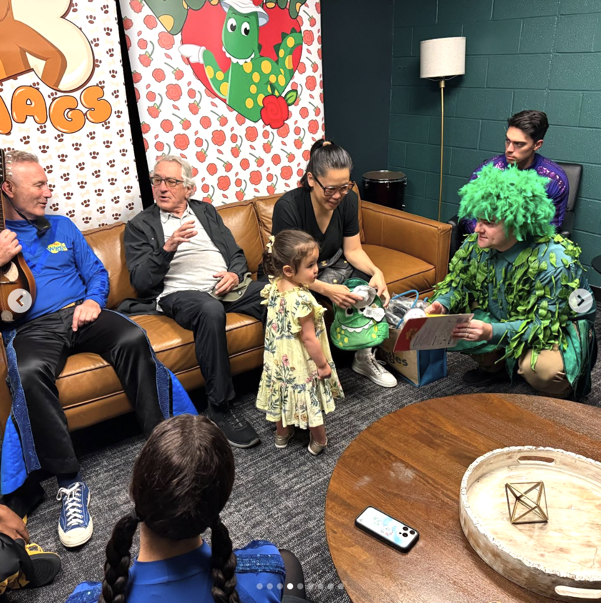 Robert De Niro sits with members of "The Wiggles" while his wife, Tiffany Chen, and their daughter Gia, interact with another member of the group on June 28, 2025 | Source: Instagram/thewiggles