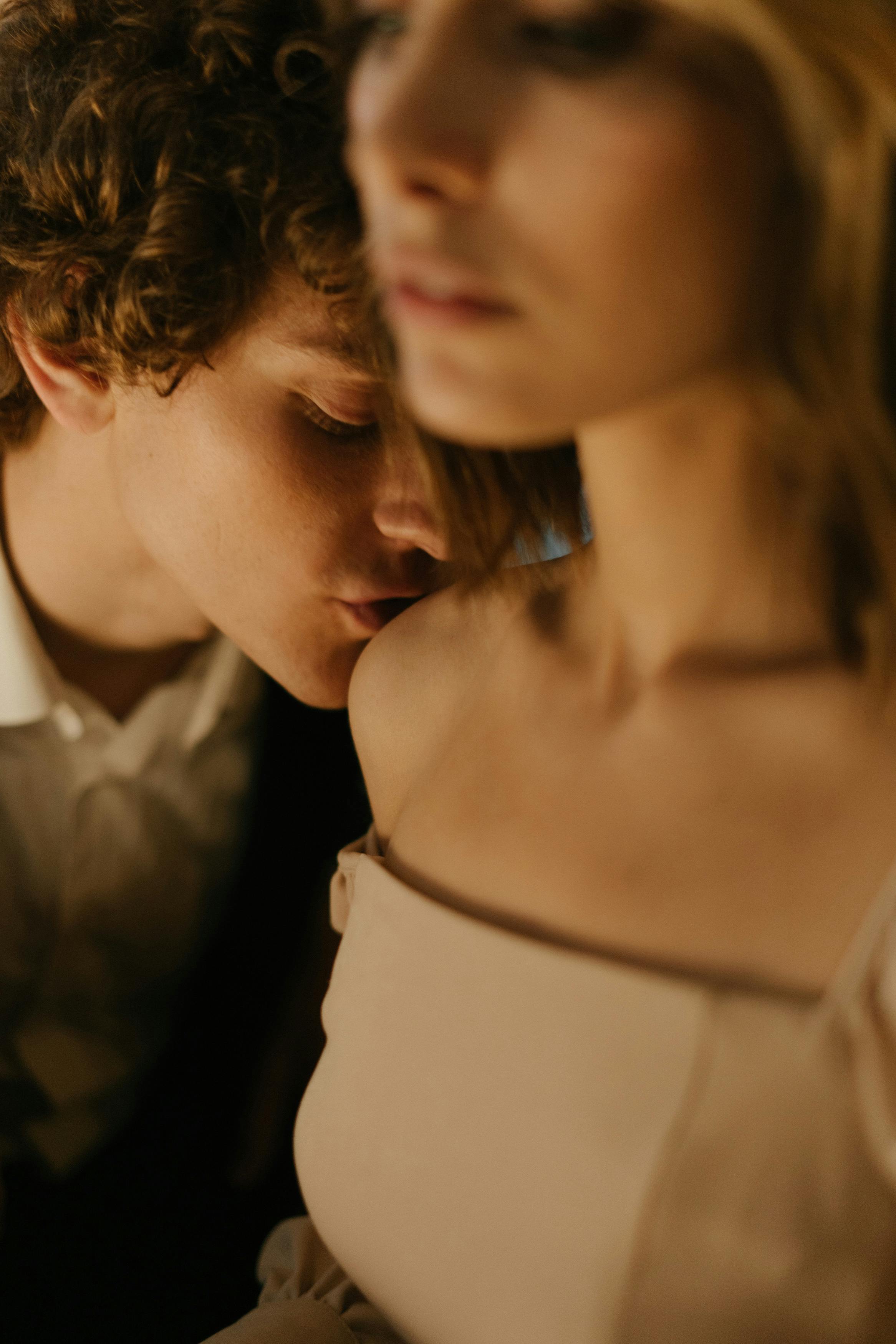 A man kissing a woman's shoulder | Source: Pexels