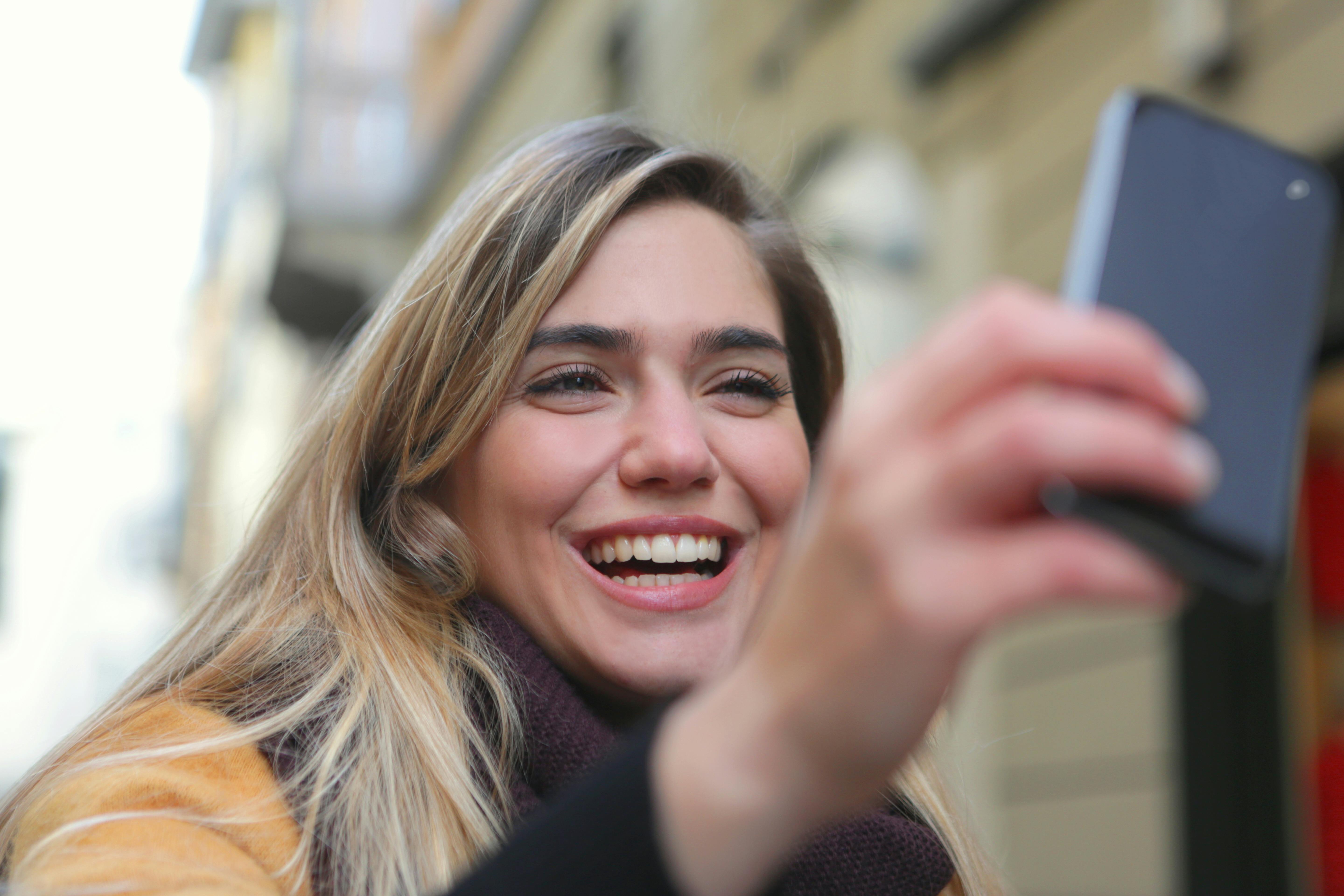 A happy woman using her phone | Source: Pexels