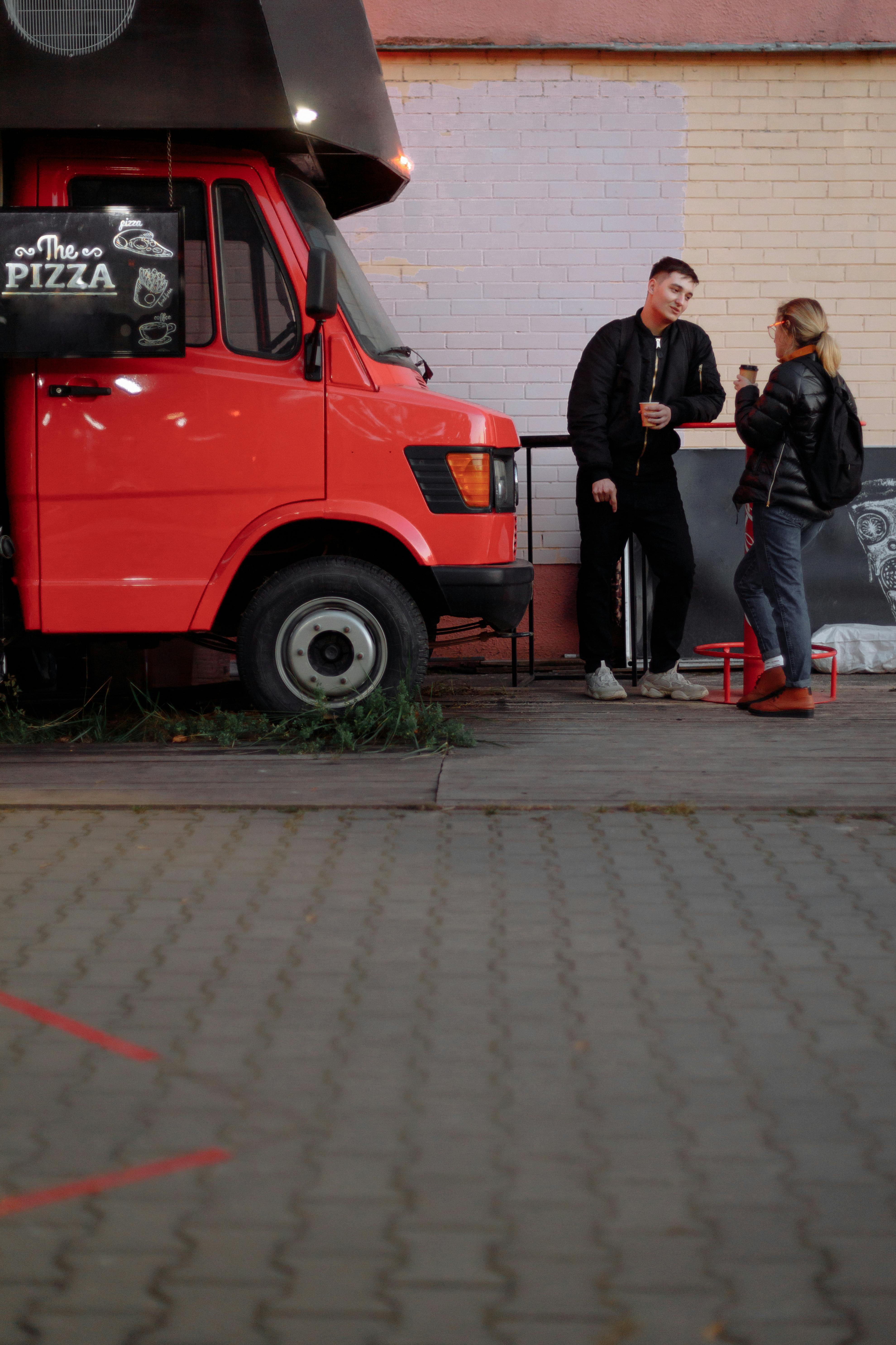 A man and a woman having coffee next to a food truck | Source: Pexels