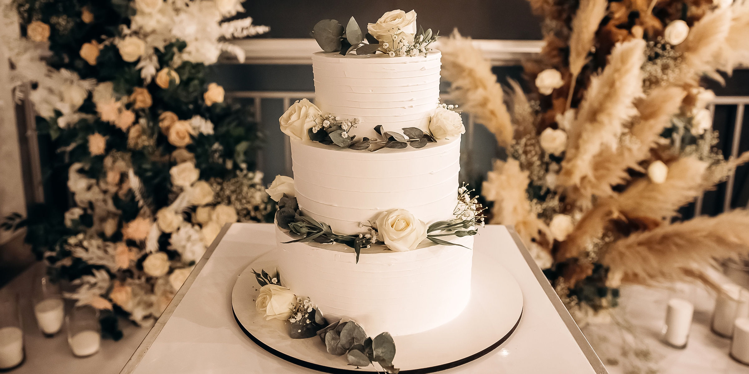 An elegant wedding cake topped with fresh roses and smooth buttercream | Source: Shutterstock