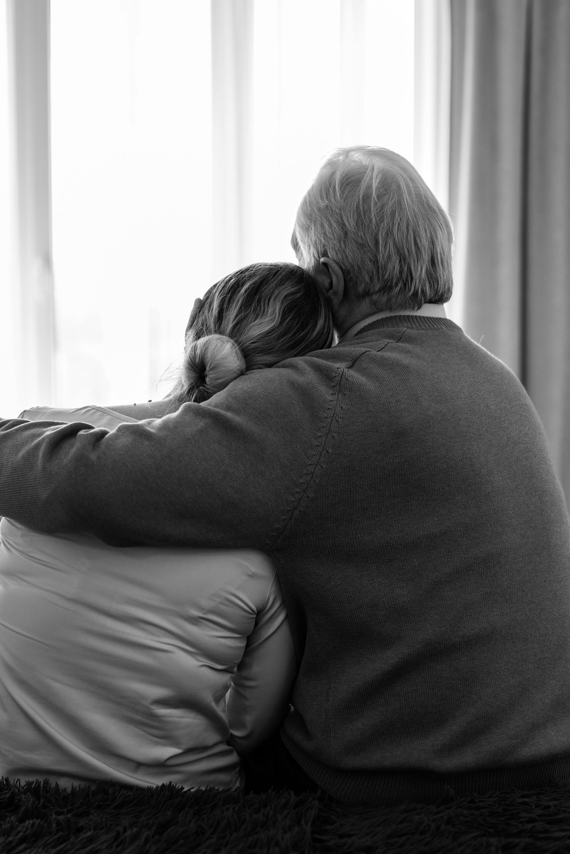 An emotional older woman leaning on her husbad's shoulder | Source: Pexels