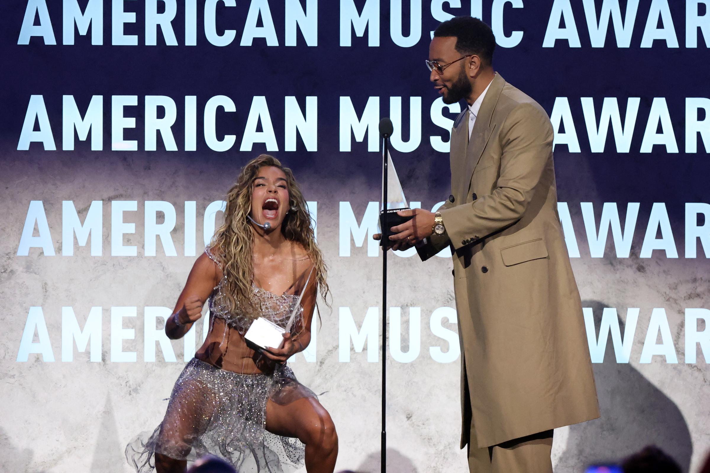 Karol G reacts as John Legend presents her with the Best Latin Album Award for "Tropicoqueta" during the American Music Awards on May 25, 2026, in Las Vegas, Nevada. | Source: Getty Images
