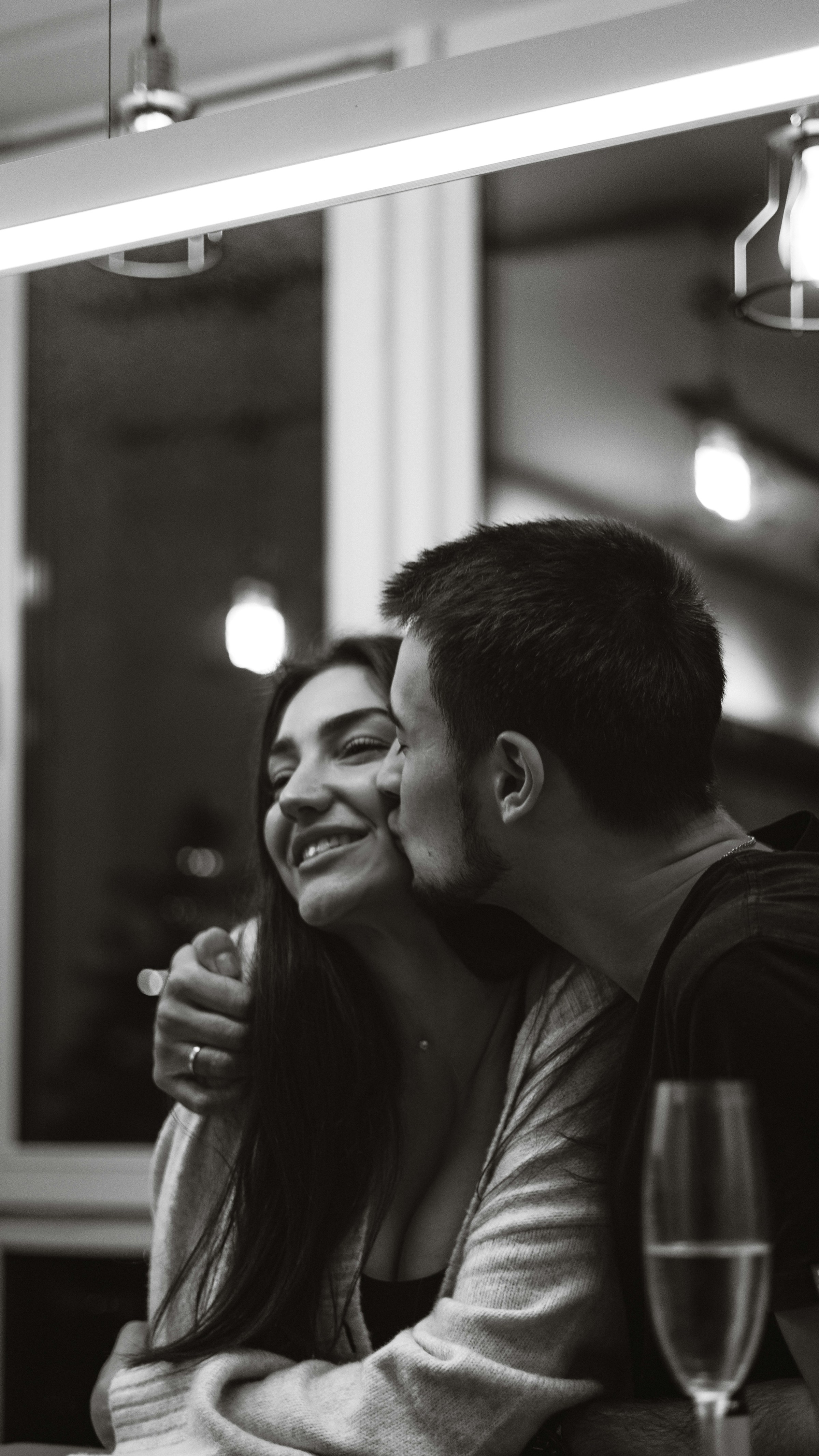 A grayscale photo of a man kissing a woman on the cheek | Source: Unsplash