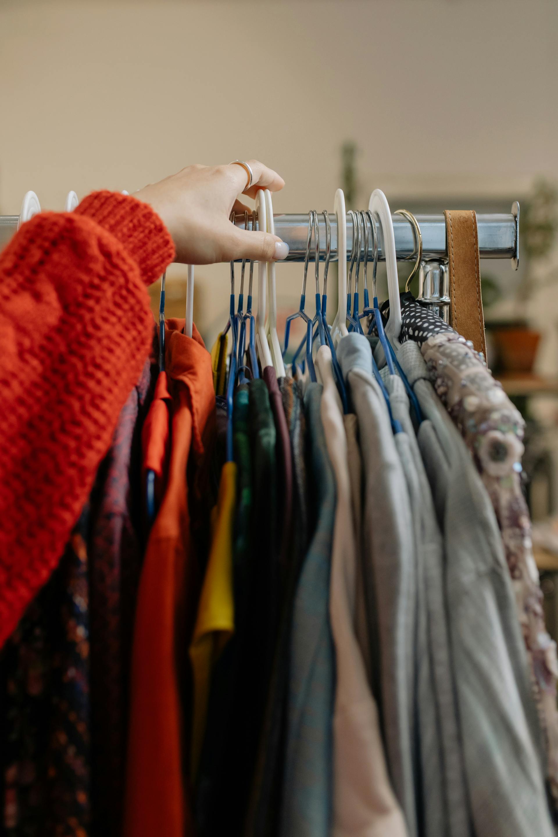 A close-up of a person touching the clothes hanging in a shop | Source: Pexels
