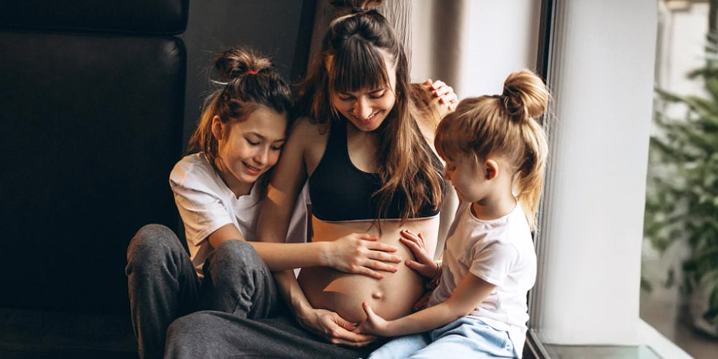 A pregnant woman with children sitting by the window | Source: Freepik