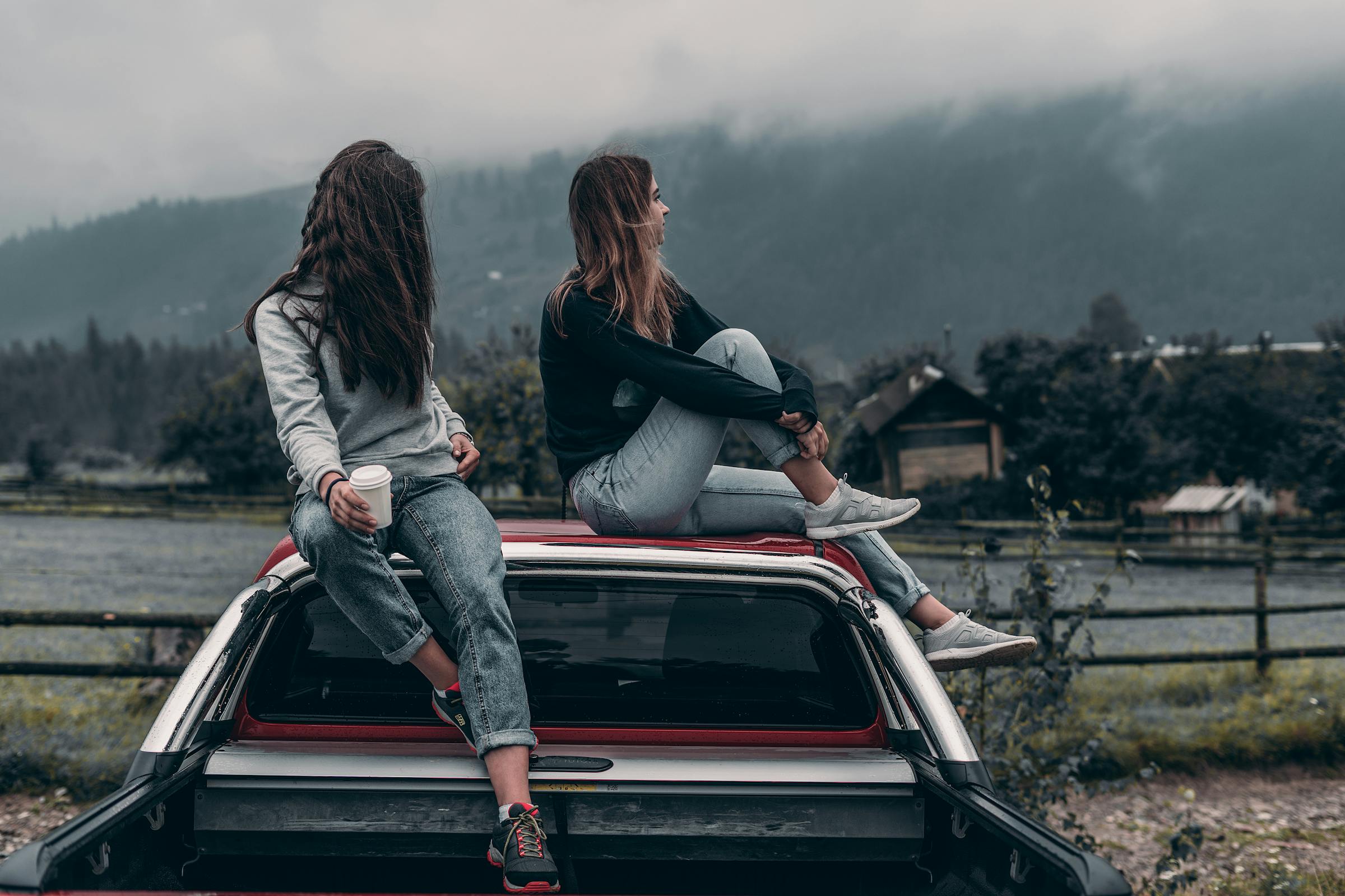 Two friends sitting on top of a car | Source: Pexels