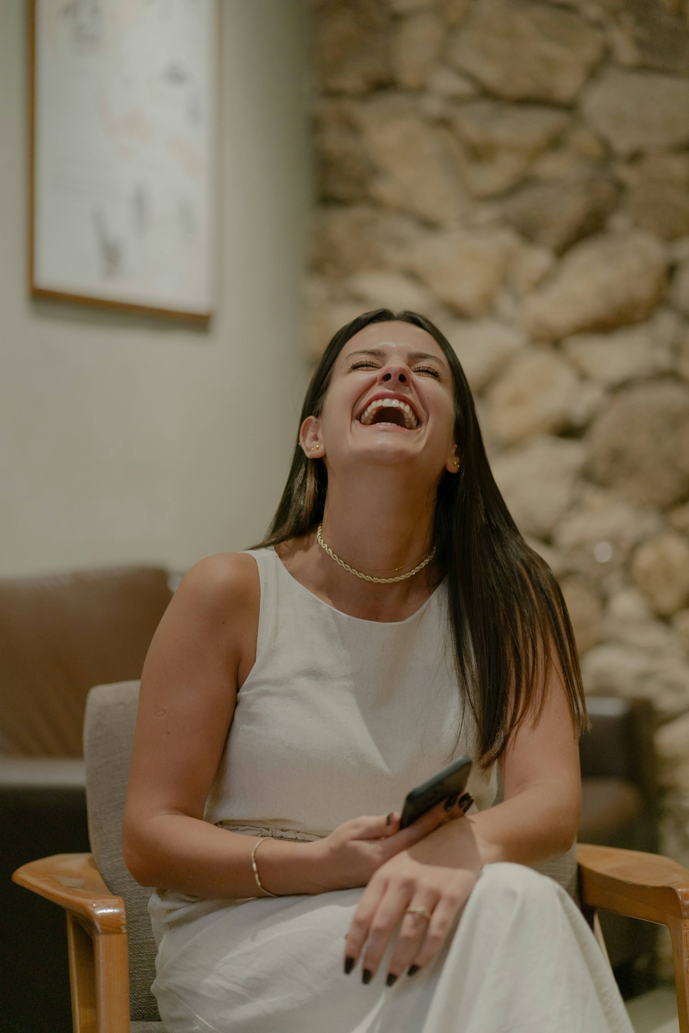 A woman laughing while holding her phone | Source: Unsplash