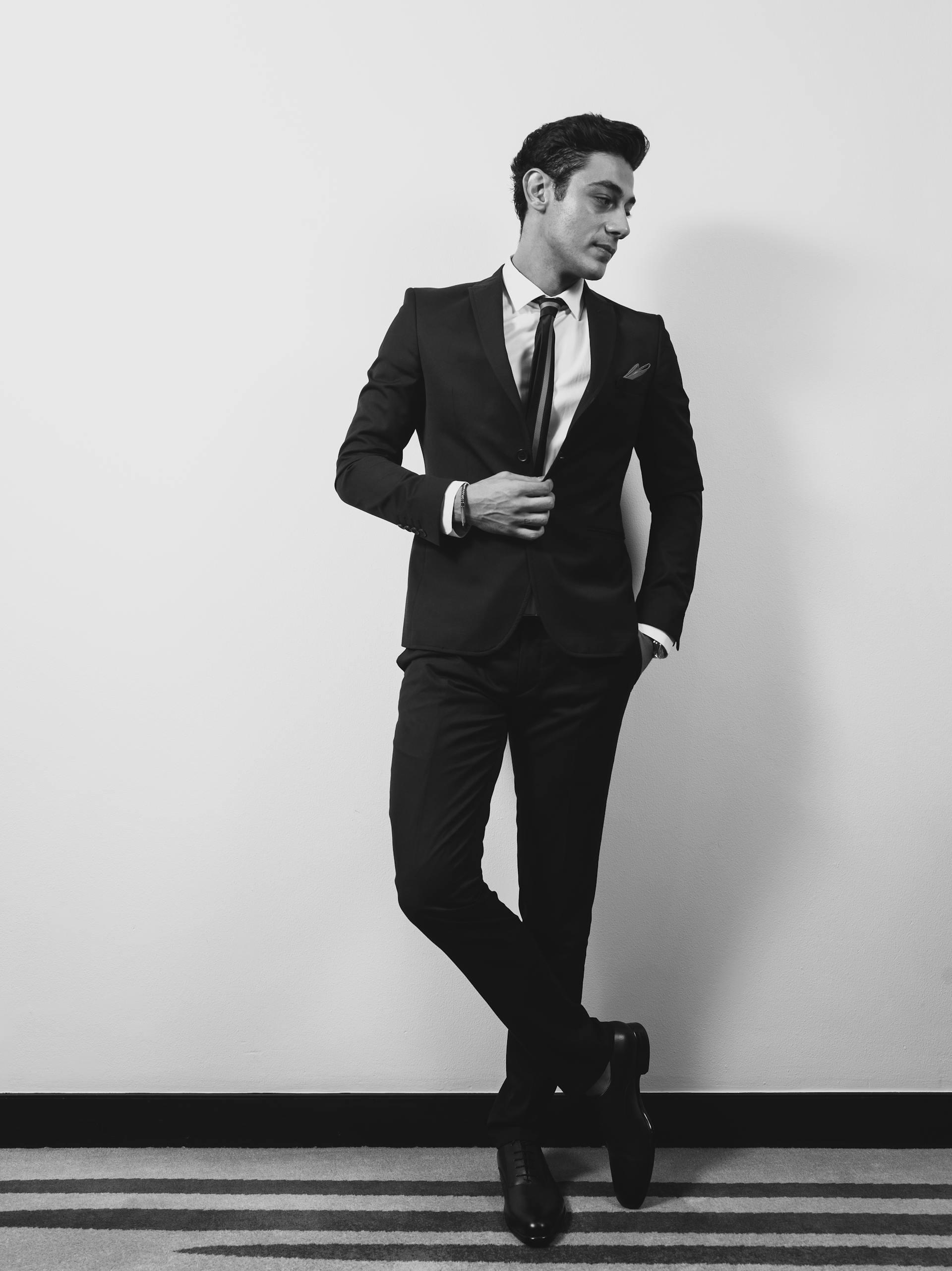 A man wearing a suit standing against a wall | Source: Pexels