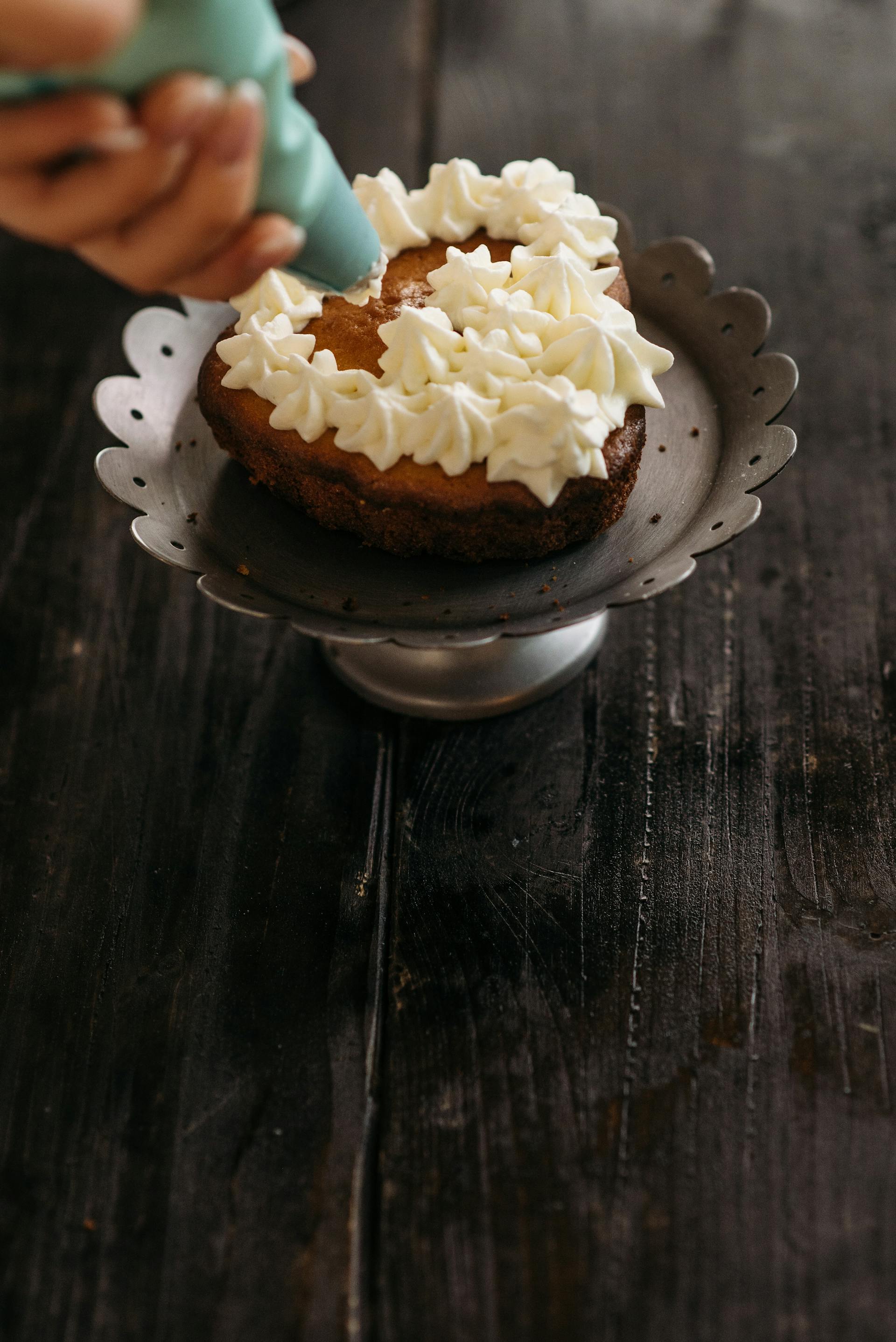 A person piping icing on a cake | Source: Pexels