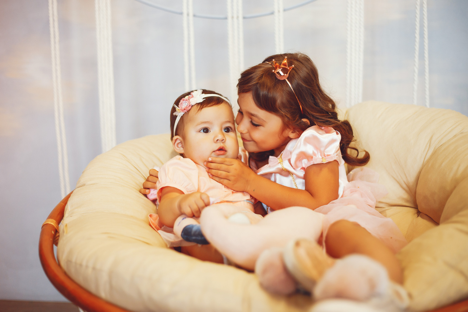 A little girl and a baby sitting on a chair | Source: Freepik
