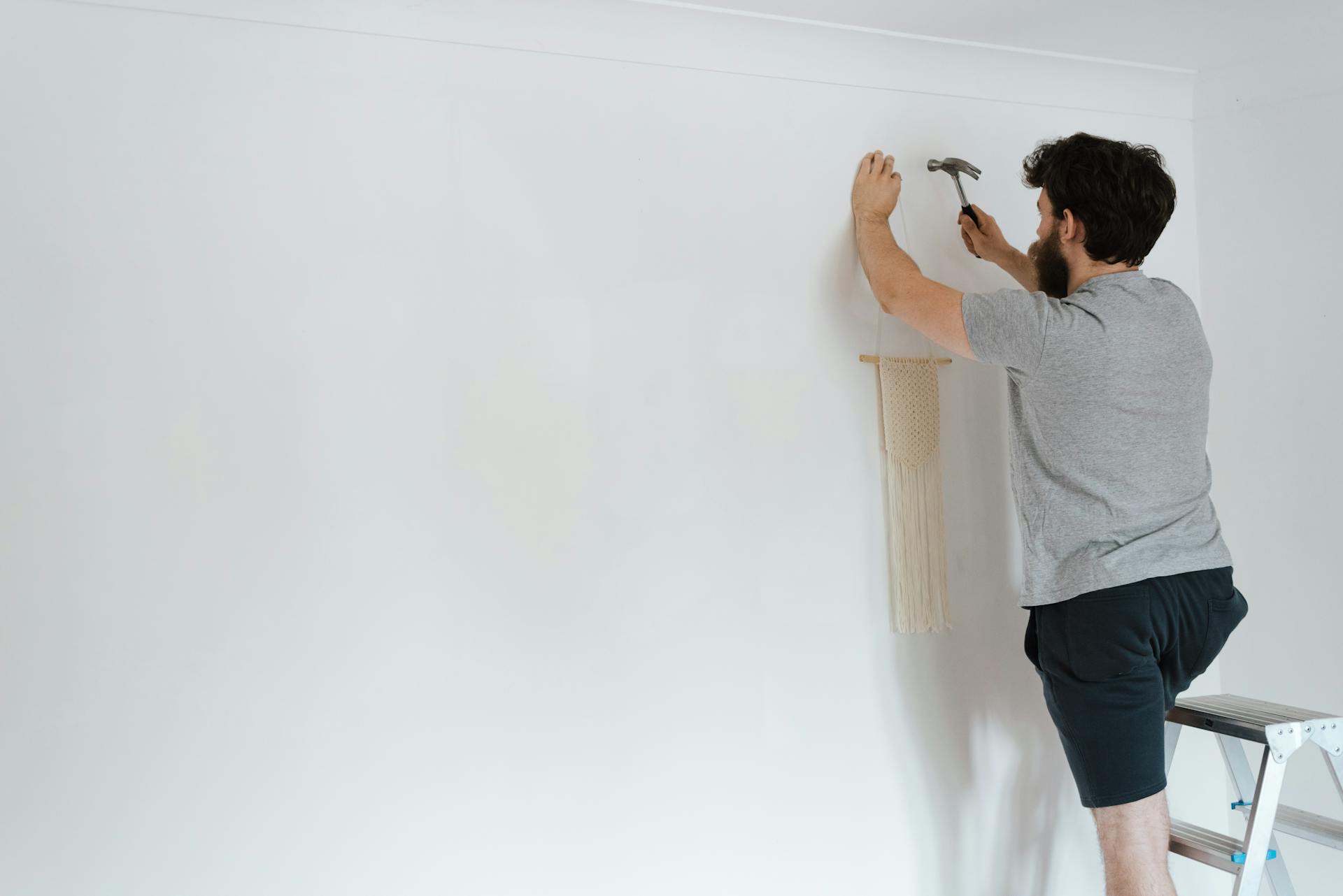 A man putting a piece of decor on a wall | Source: Pexels