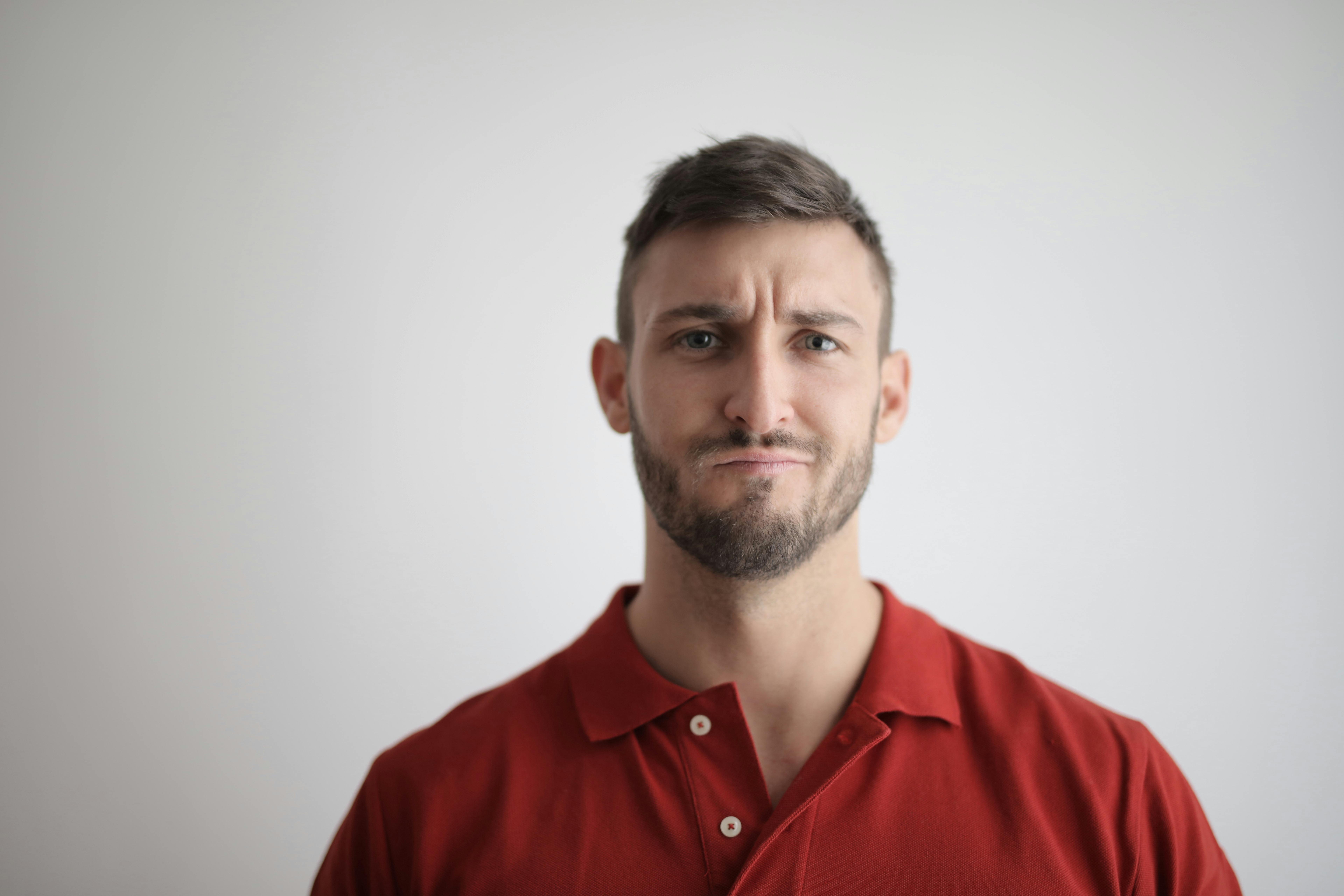 A frowning man wearing a red polo shirt | Source: Pexels