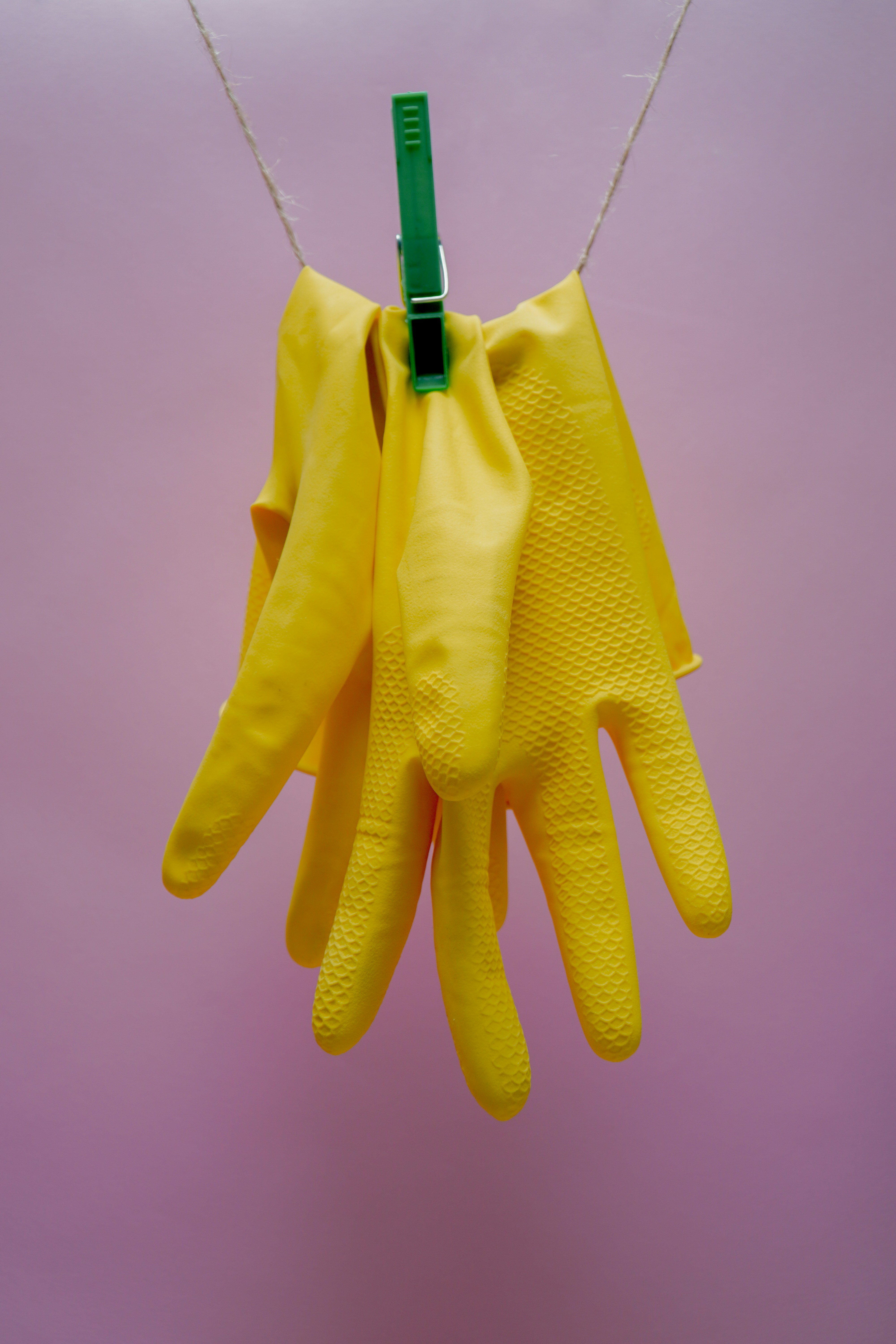 Yellow gloves hanging with a peg | Source: Unsplash
