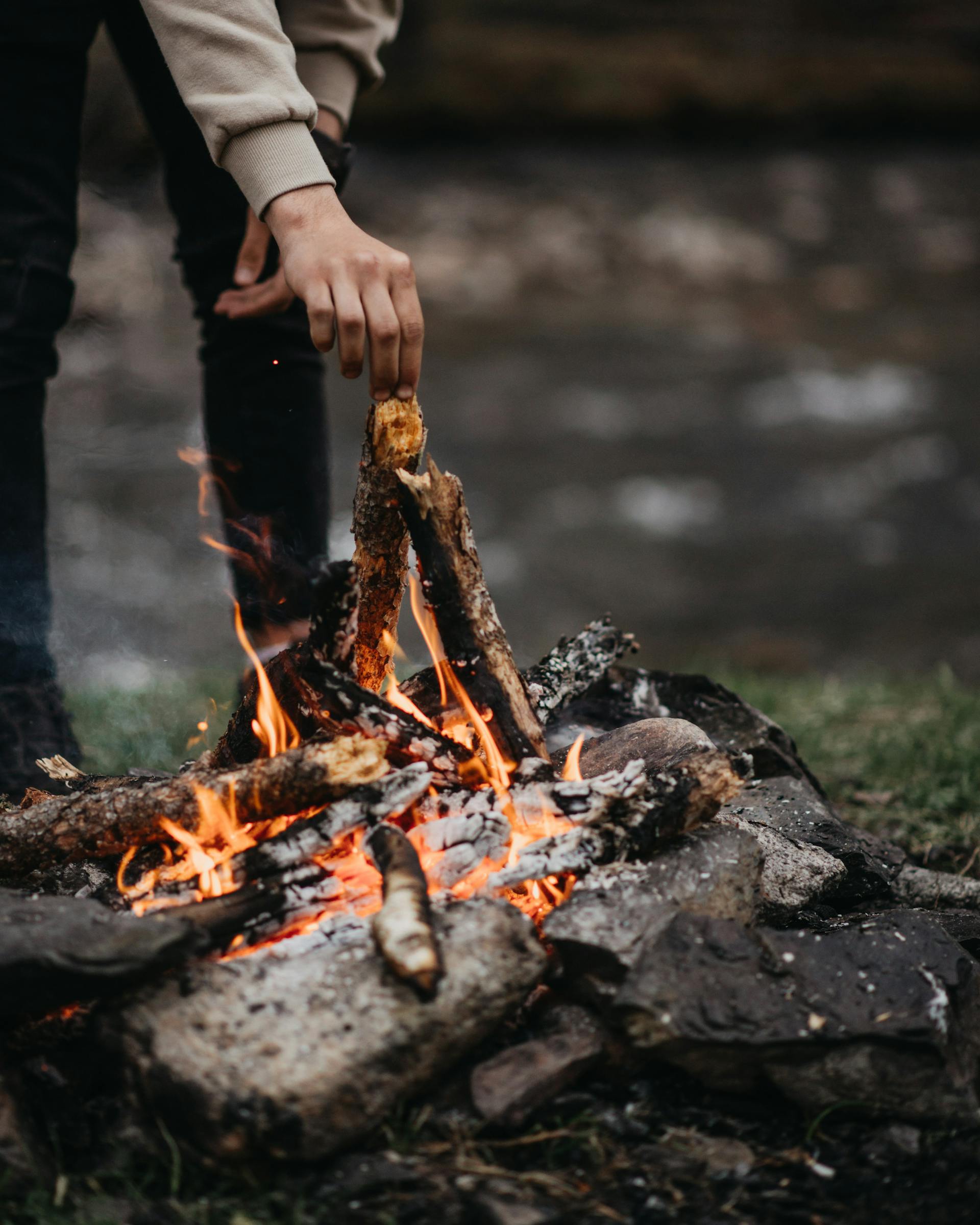 A man adding wood to a fire | Source: Pexels