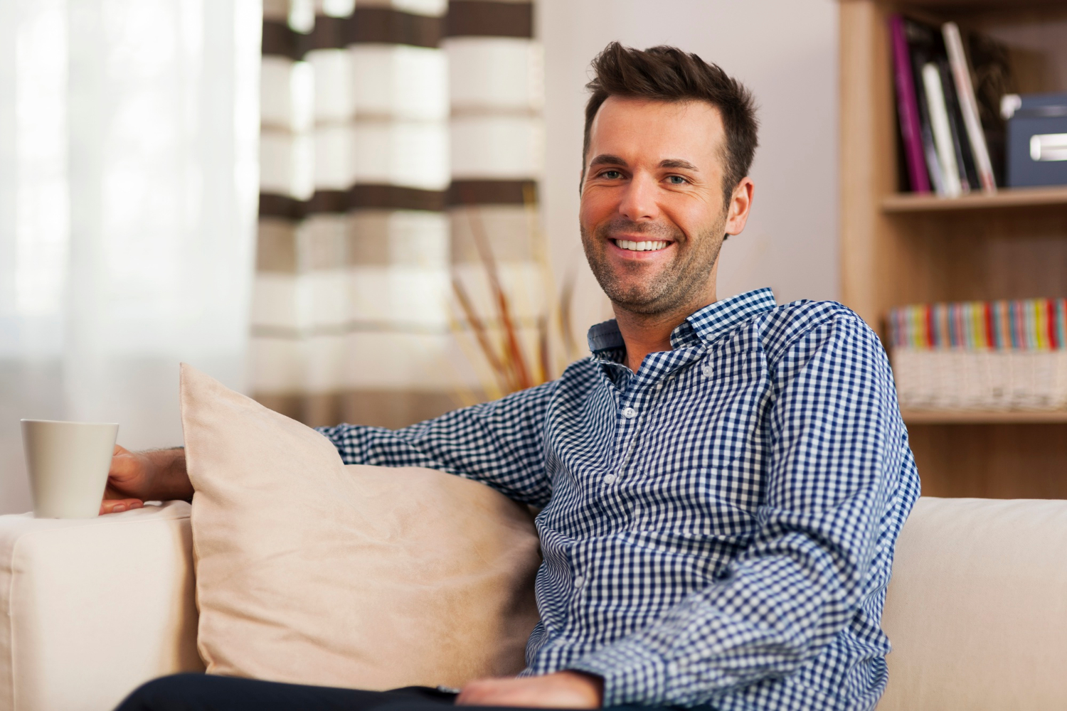 A man sitting on the couch and smiling | Source: Freepik