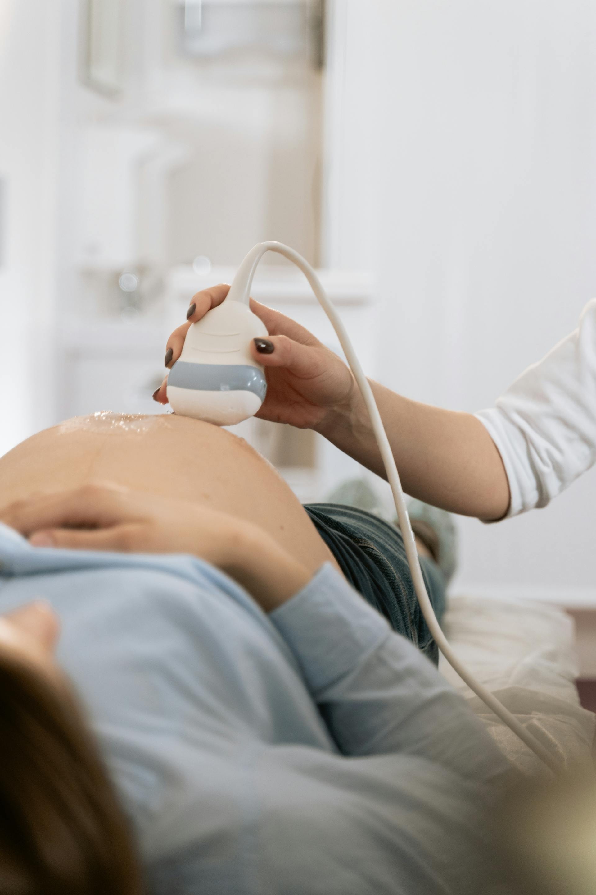 A pregnant woman lying down and getting her ultrasound done | Source: Pexels