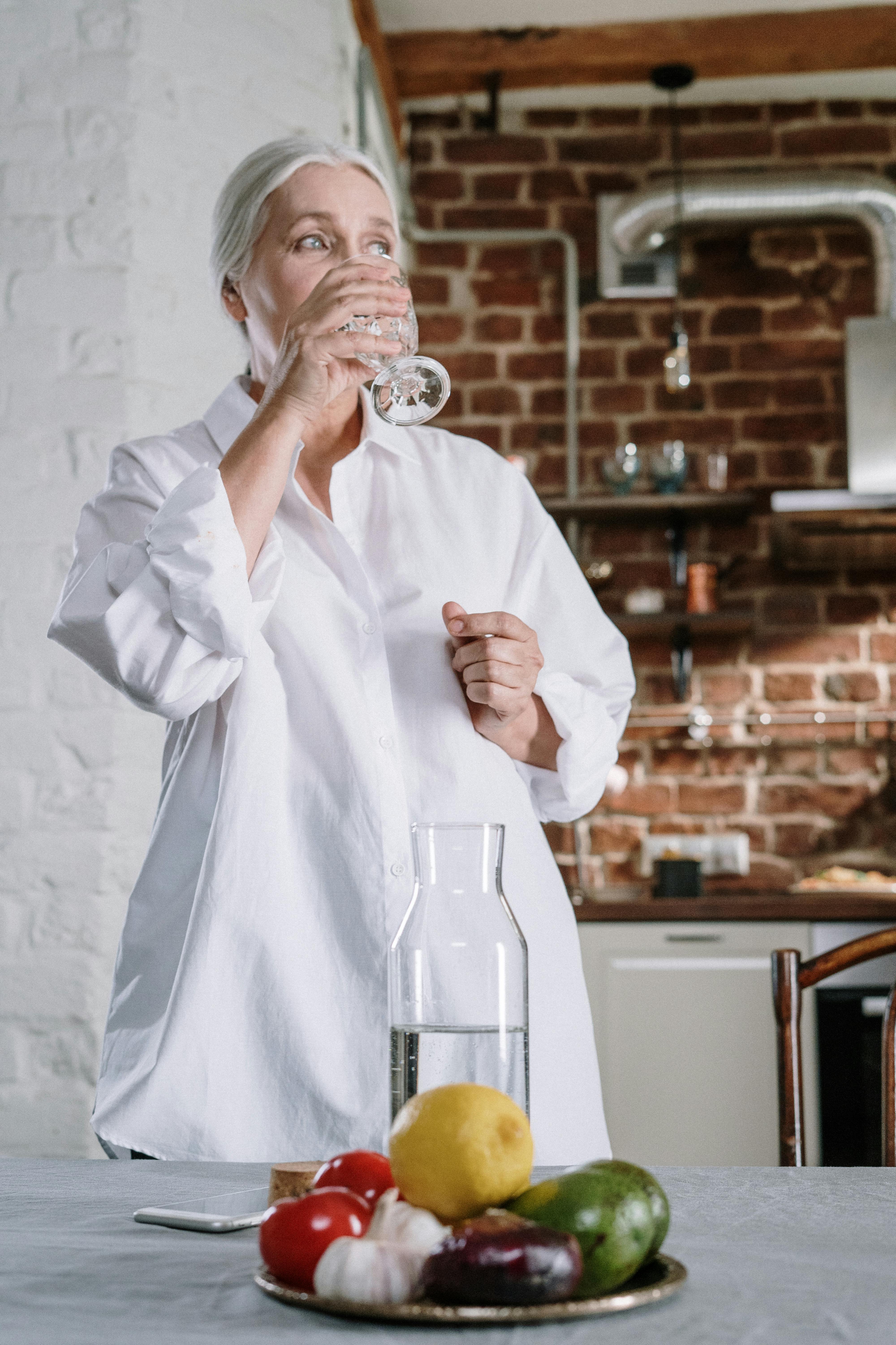 An older woman drinking a glass of water | Source: Pexels