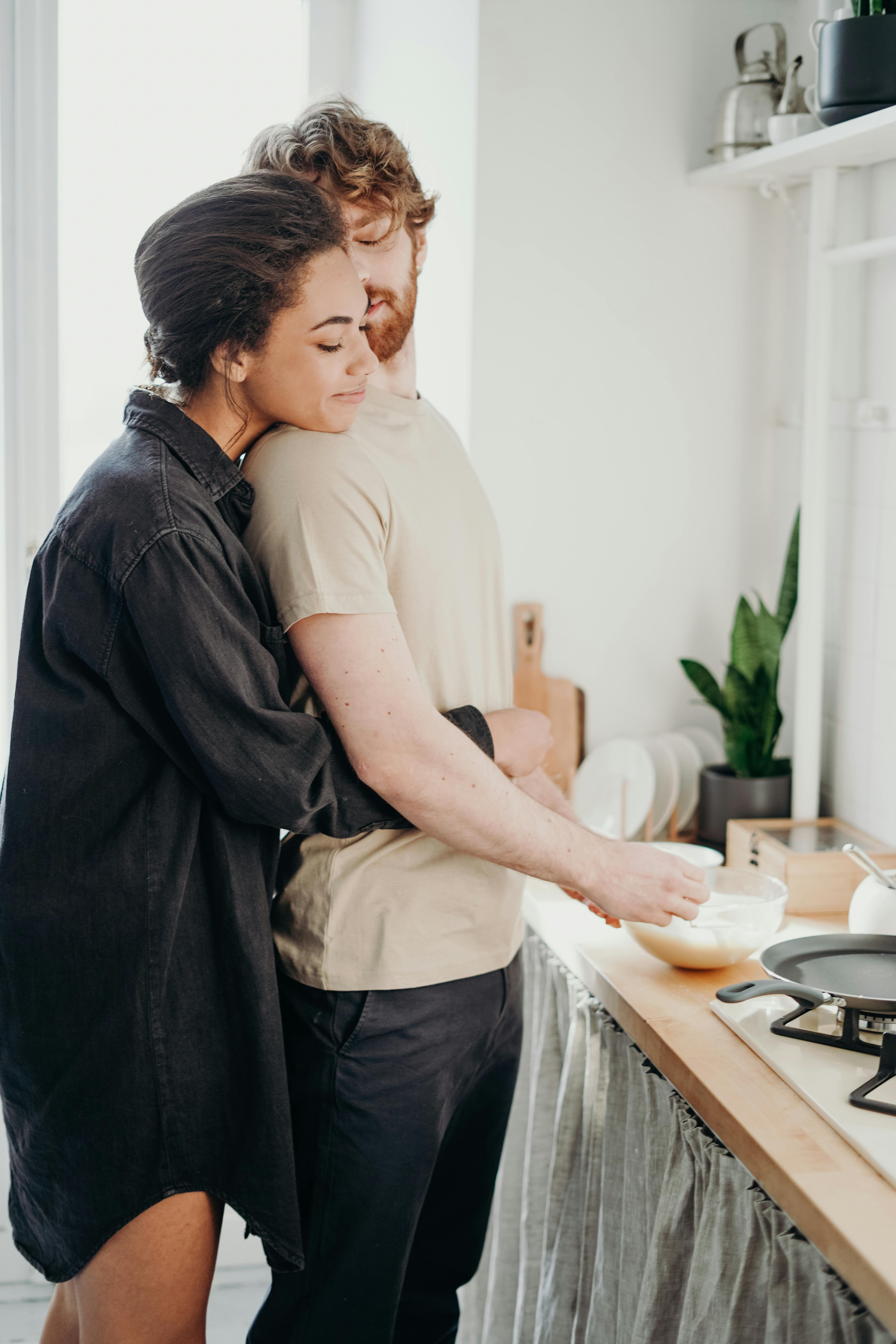 A woman hugging a man while he cooks | Source: Pexels