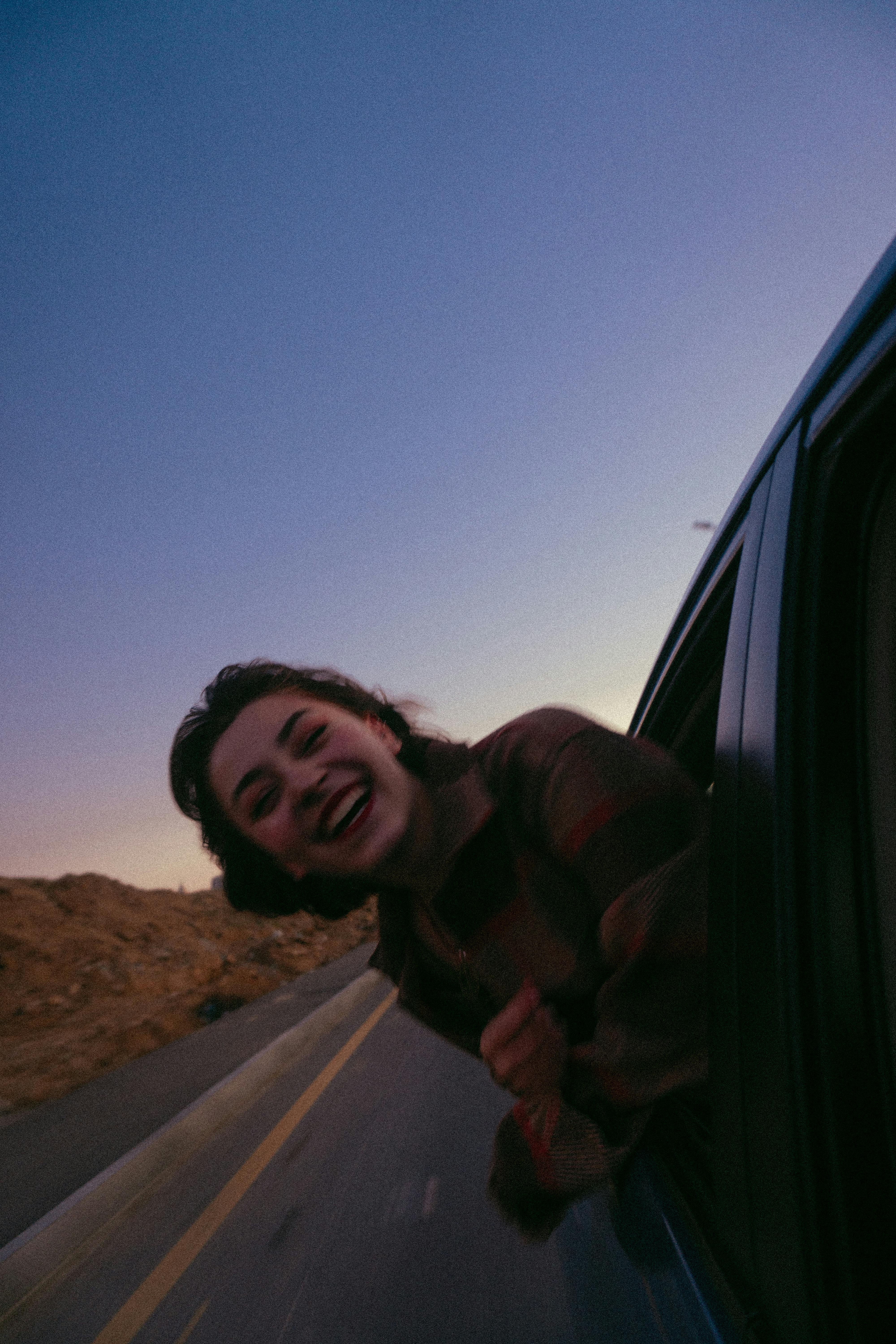 A smiling teenage girl with her head out a car window | Source: Pexels