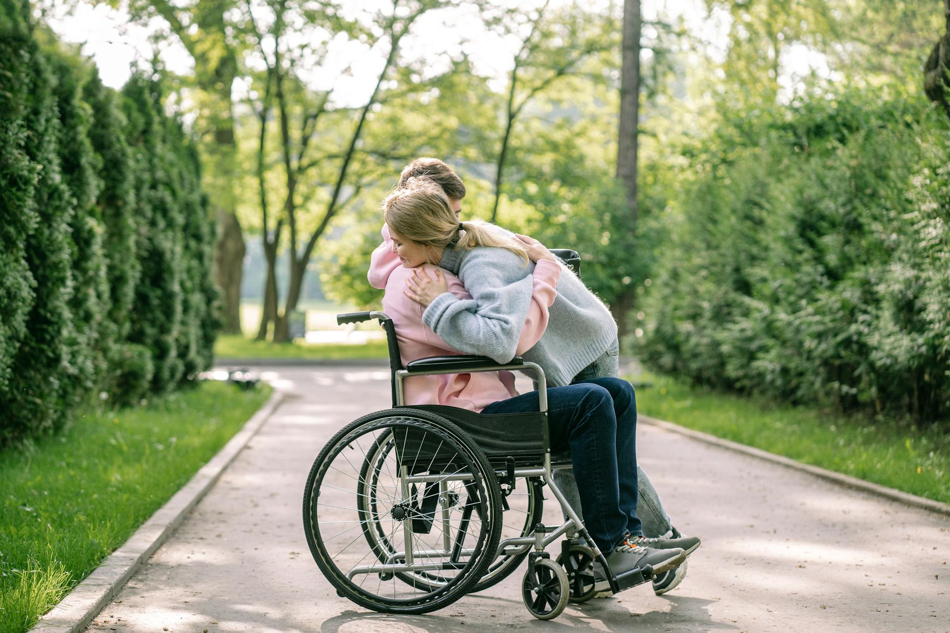A woman hugging a man in a wheelchair | Source: Pexels