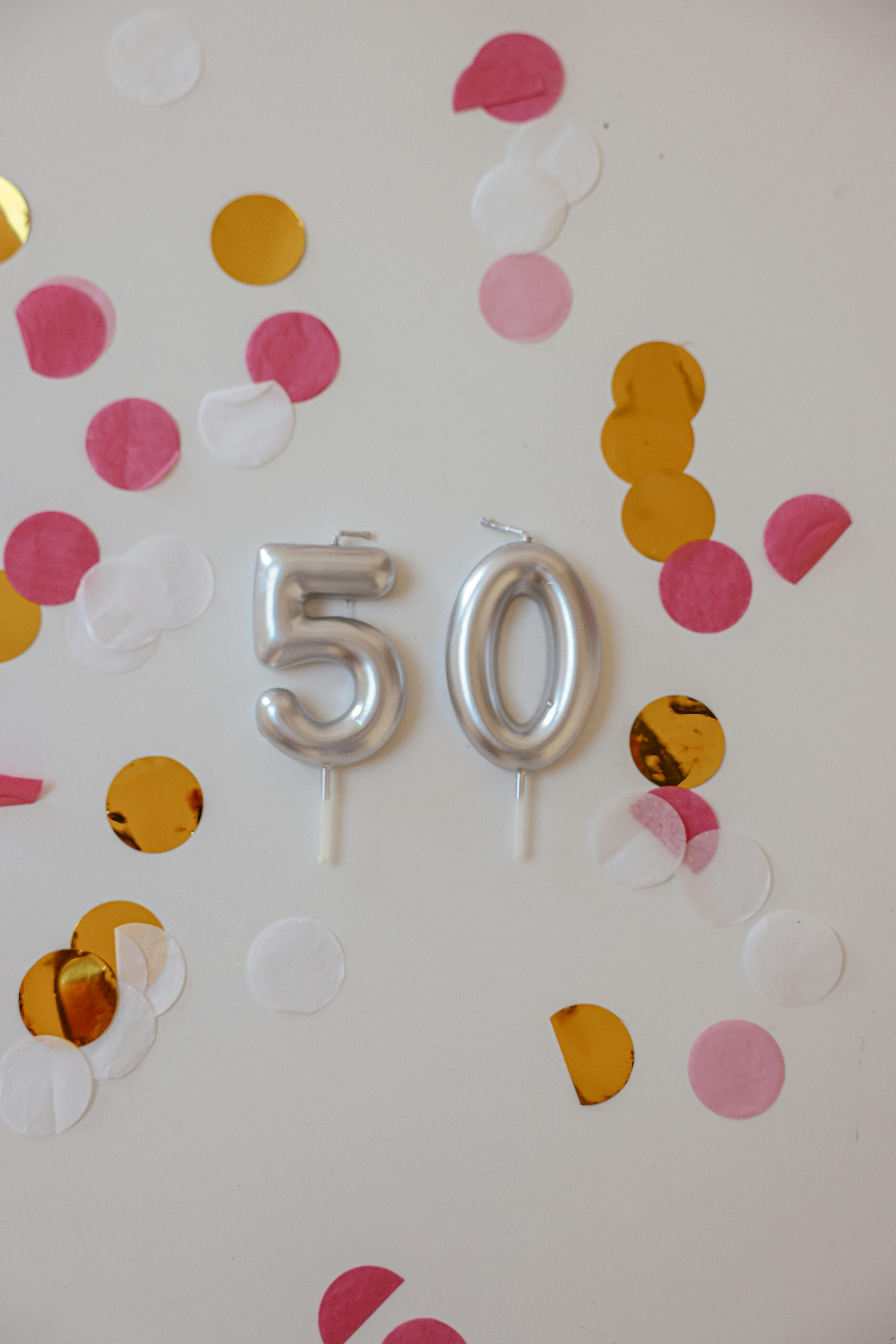 Silver balloons and colorful confetti on a wall | Source: Pexels