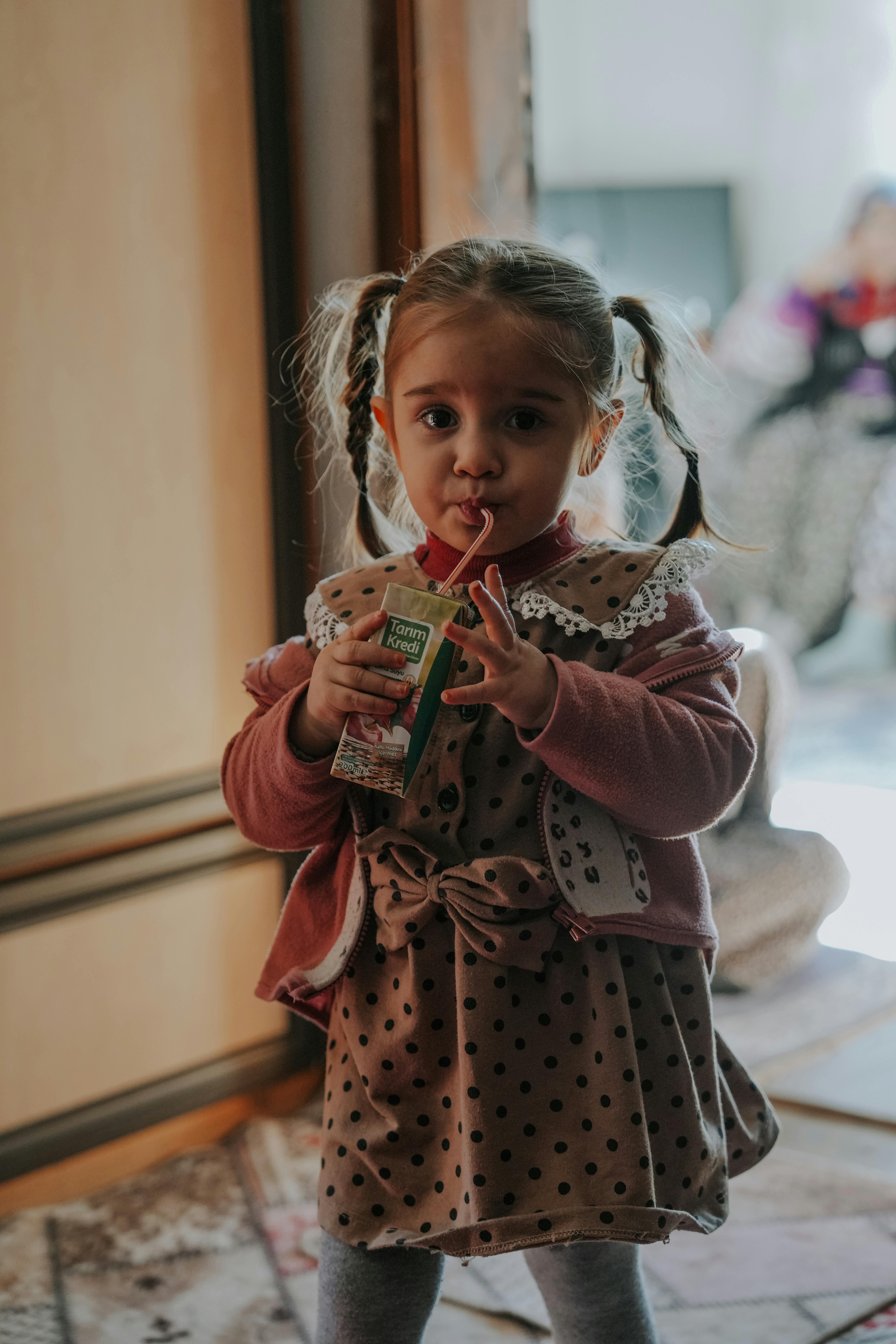 A little girl drinking from a juice box | Source: Pexels