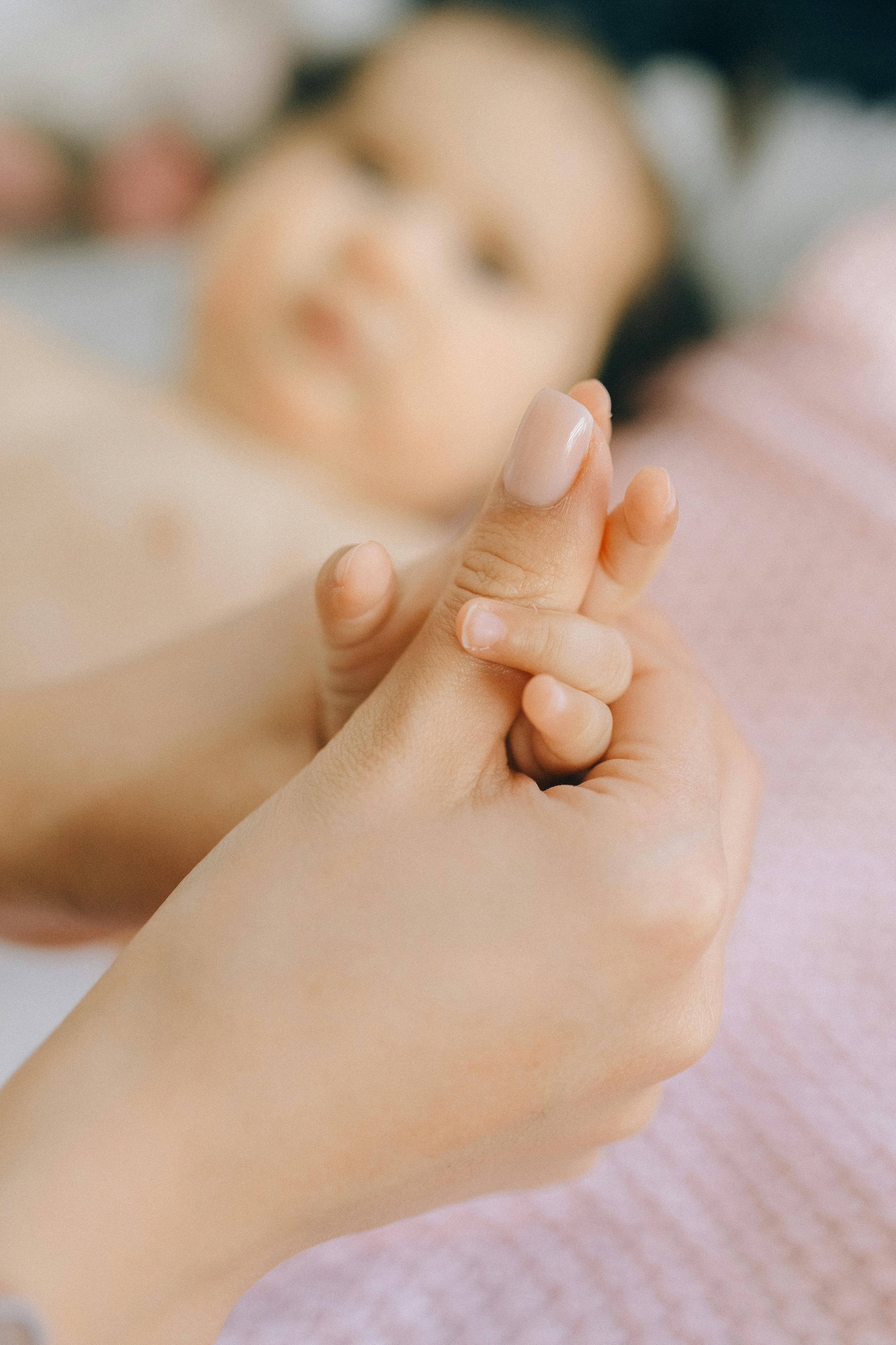 A woman holding a baby's hand | Source: Pexels