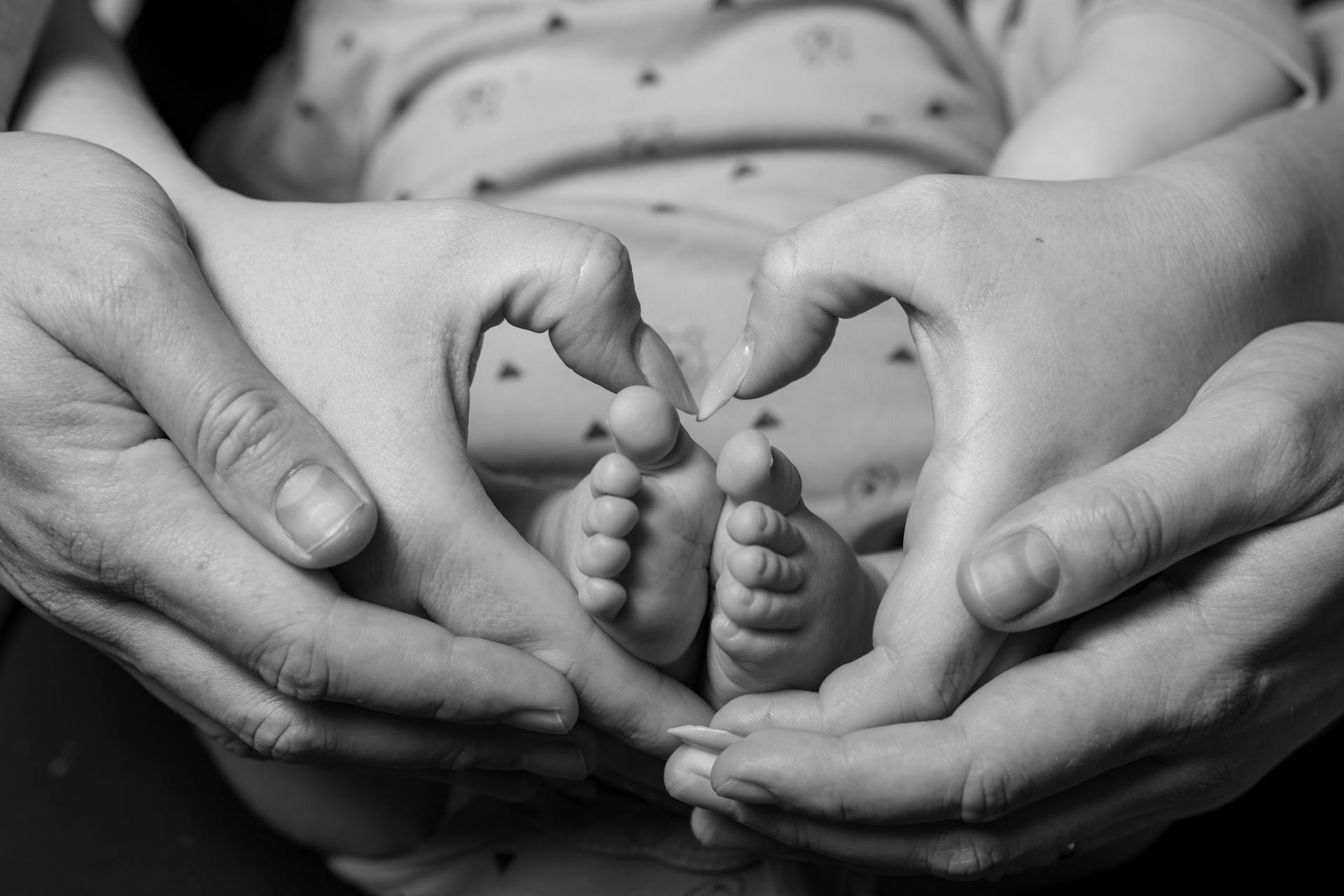 A couple making a heart-shaped sign around their baby's feet | Source: Pexels