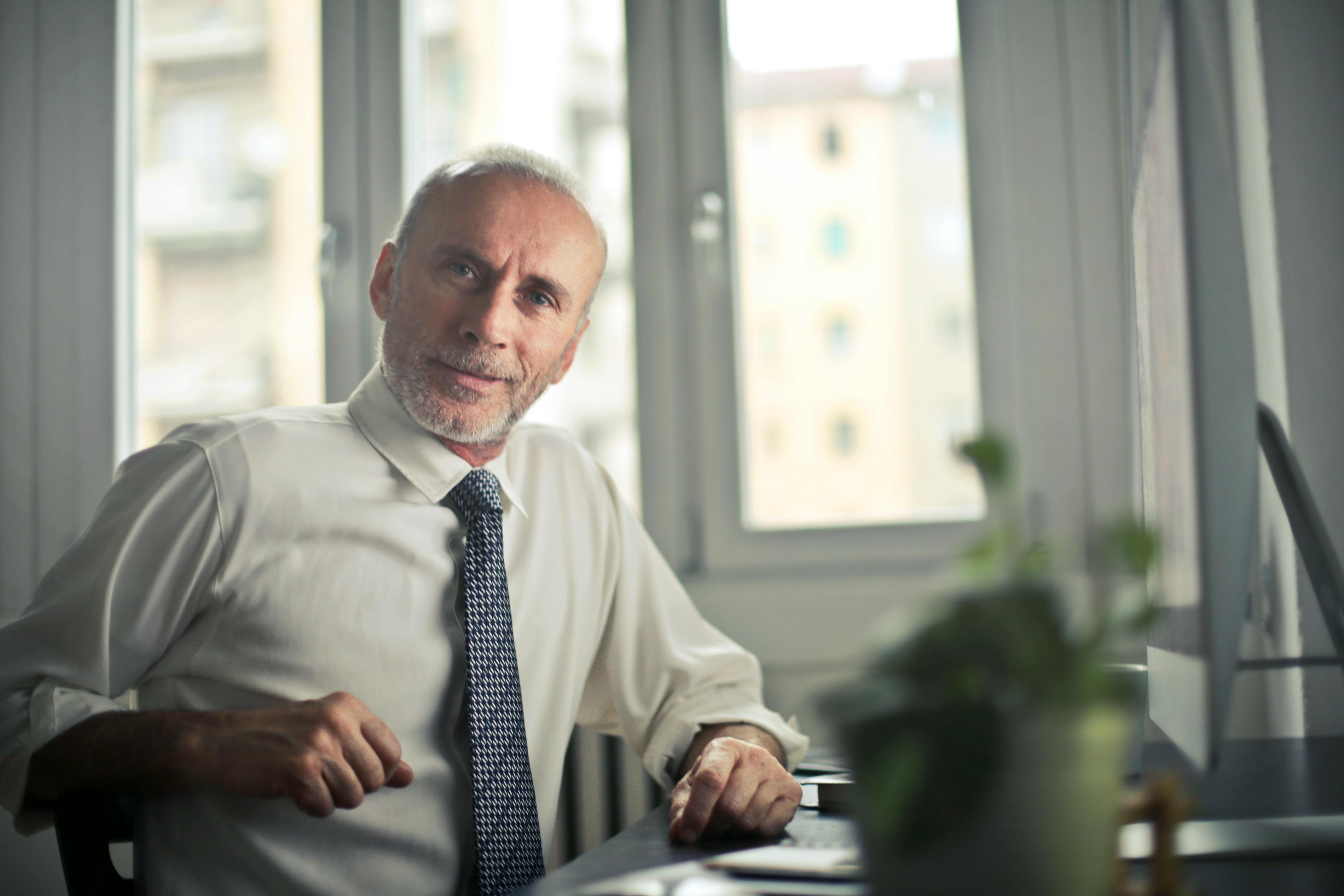 A smiling man sitting at a desk | Source: Pexels
