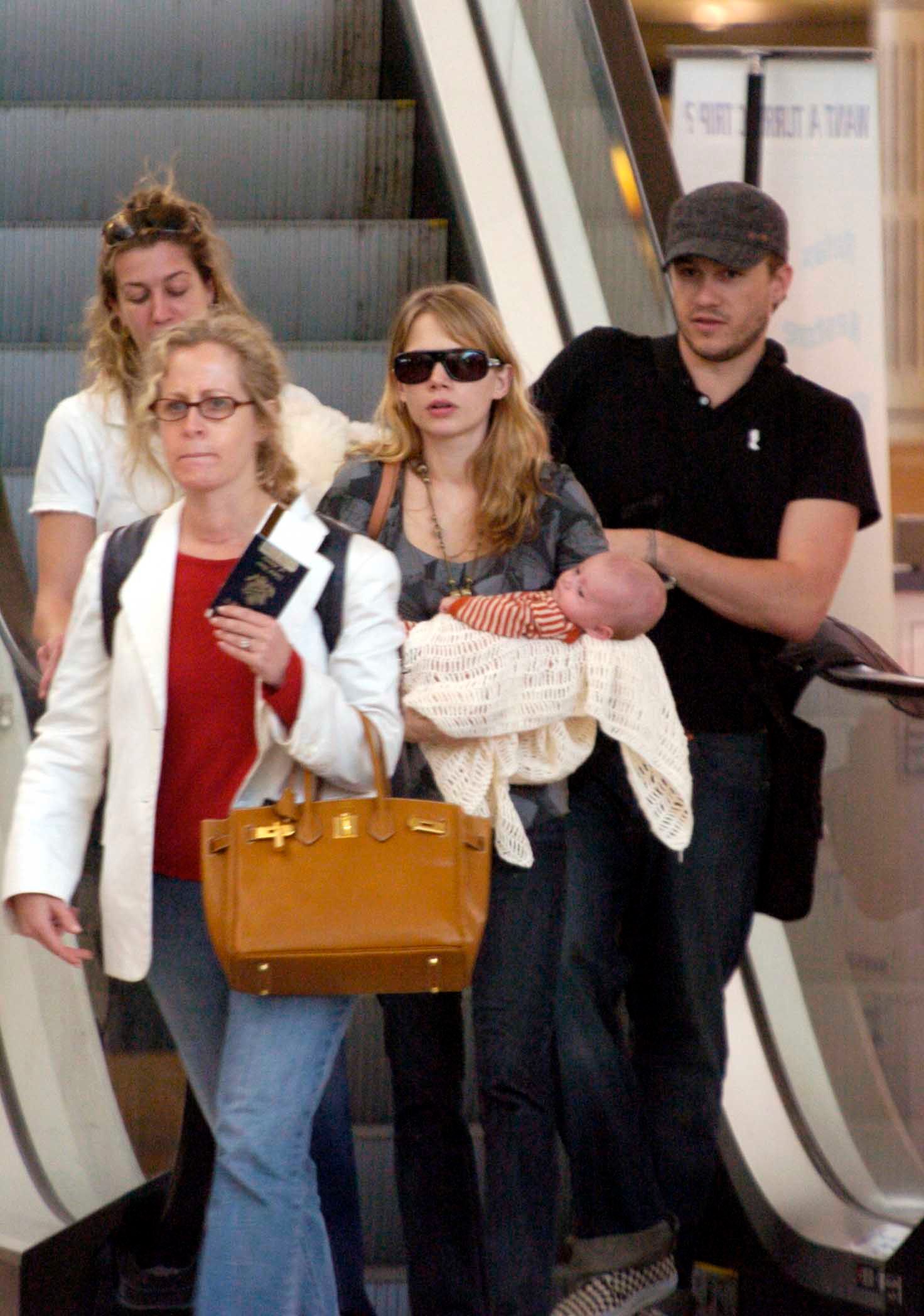 Michelle Williams carrying daughter Matilda, with Heath Ledger at the Sydney International Airport on January 14, 2006 | Source: Getty Images