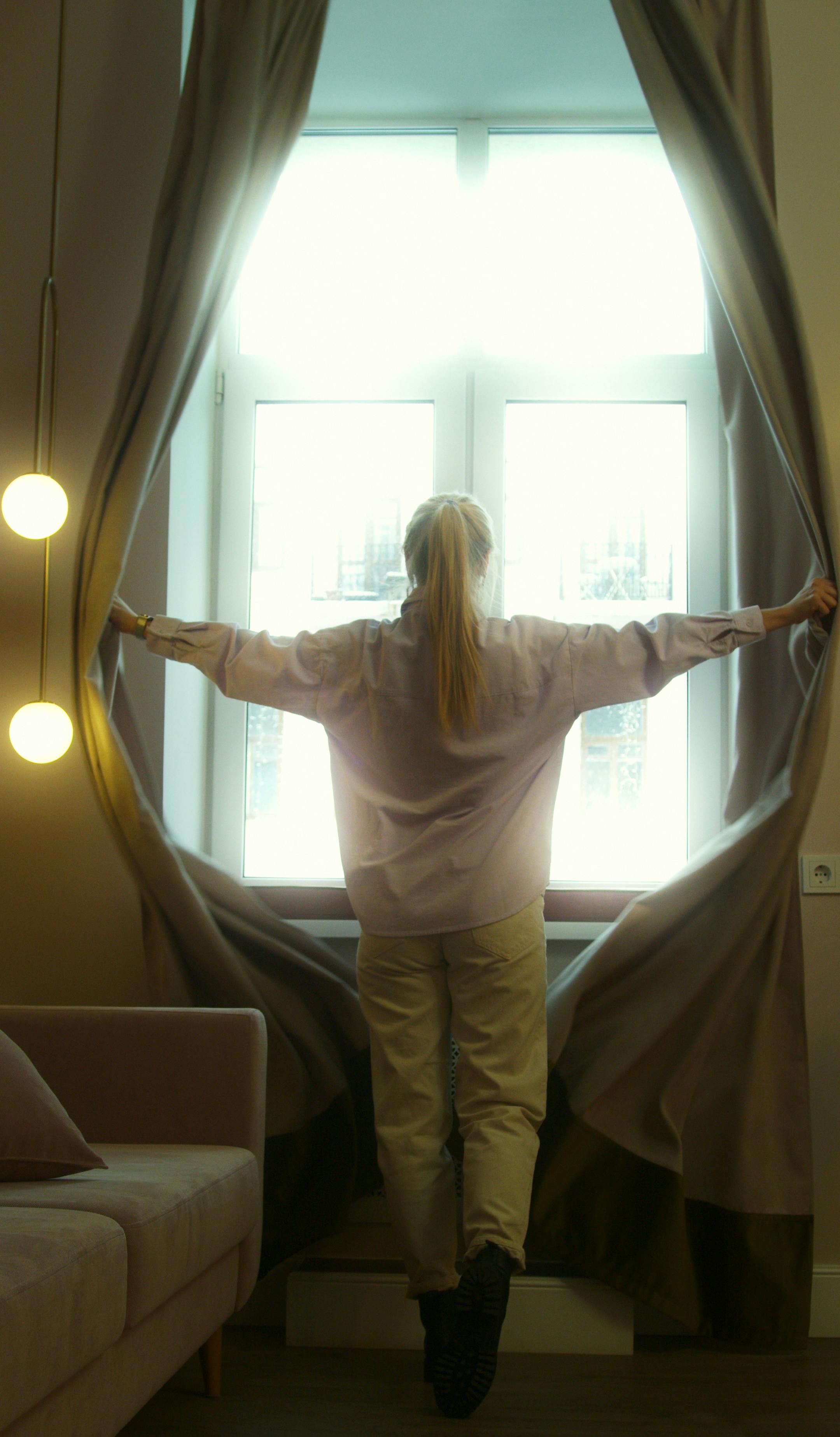 A woman opening her curtains | Source: Pexels