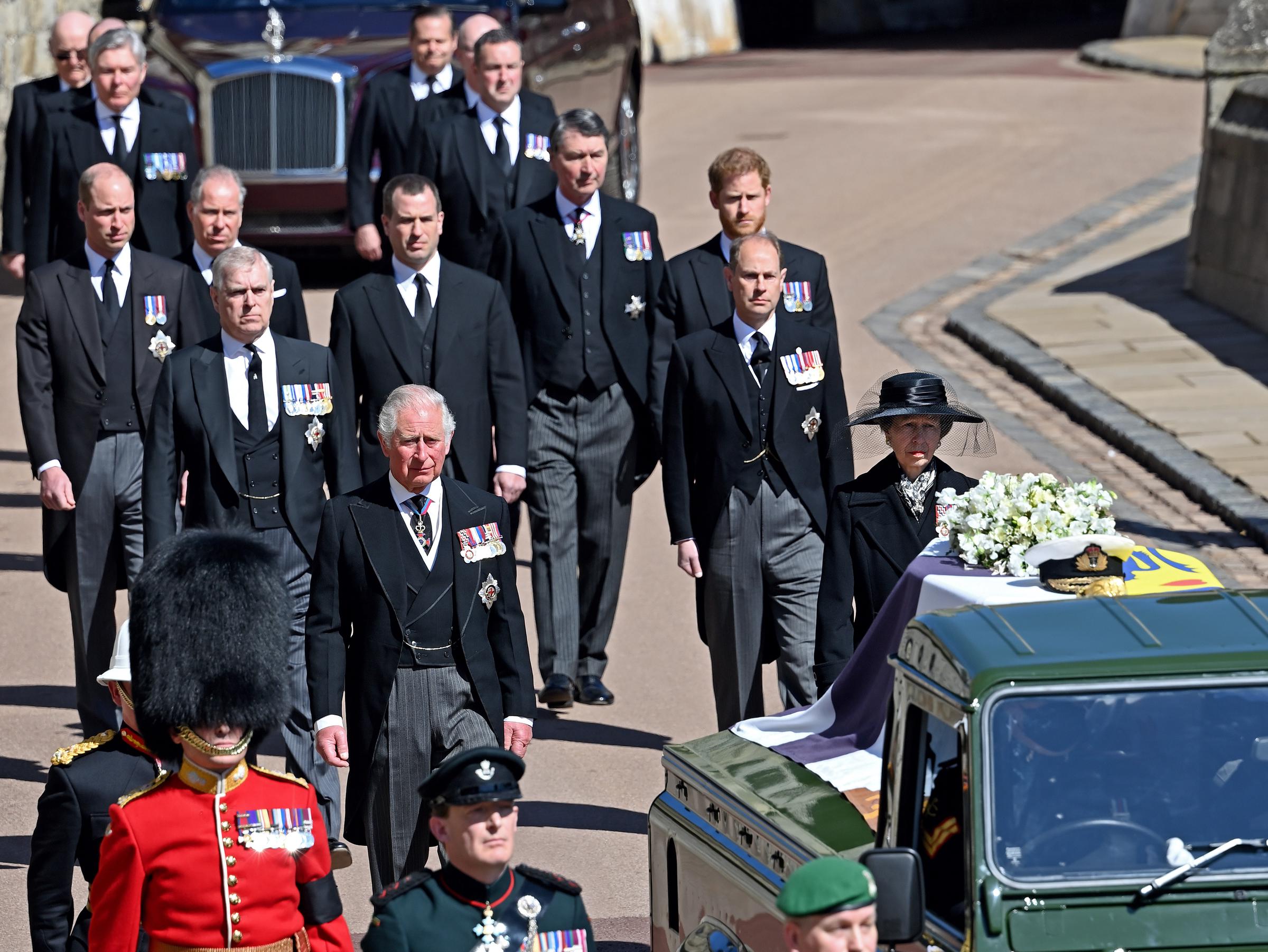 Prince Harry (centre right) and family follow Prince Philip, Duke of Edinburgh's coffin (draped in his Royal Standard Flag and bearing his Royal Navy cap, sword and a bouquet of lilies, white roses, freesia and sweet peas) as it is carried on a specially designed Land Rover Defender hearse during his funeral procession to St. George's Chapel, Windsor Castle on April 17, 2021 in Windsor, England. | Source: Getty Images